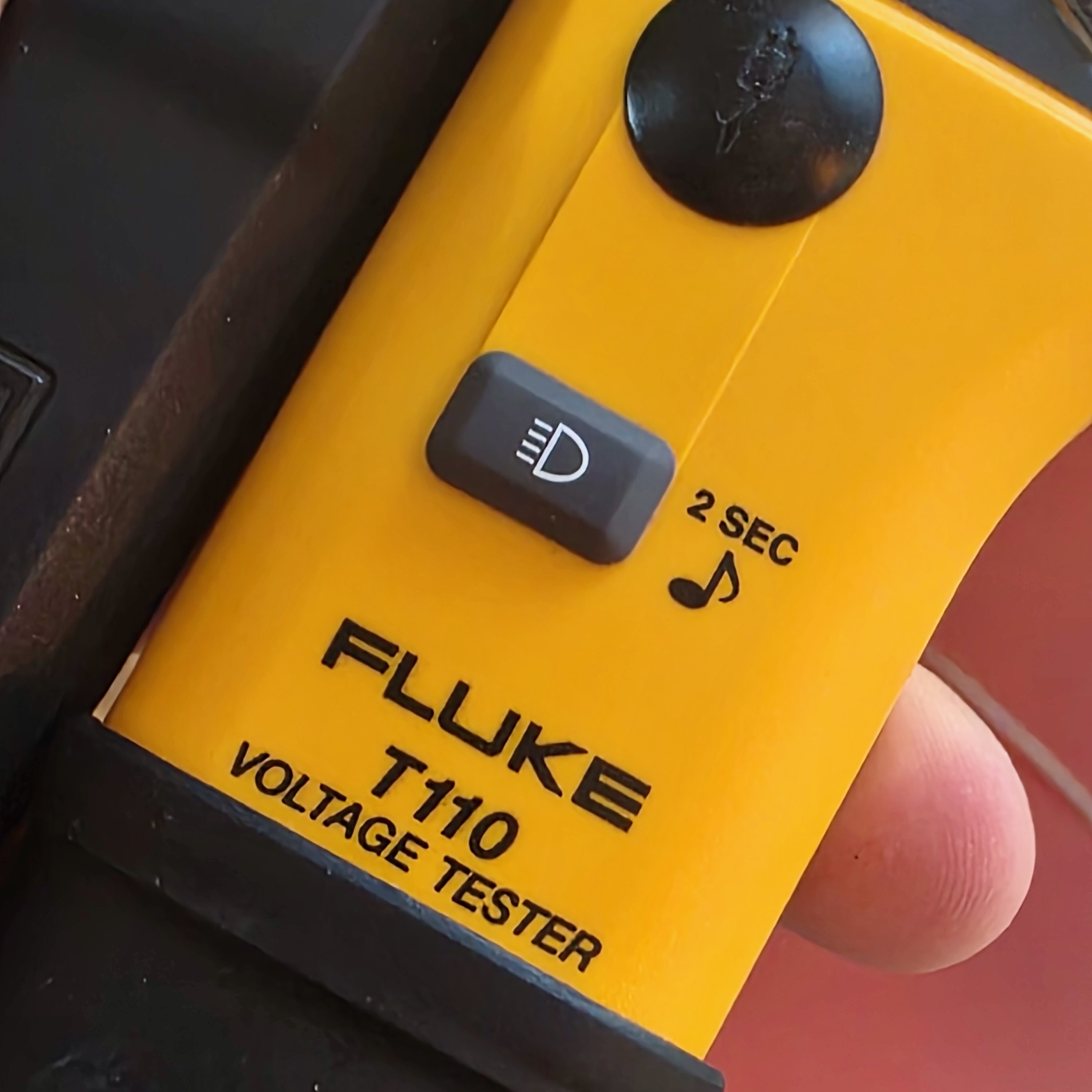 Close-up VAT Fluke T110 et bouton lampe — détail ergonomie