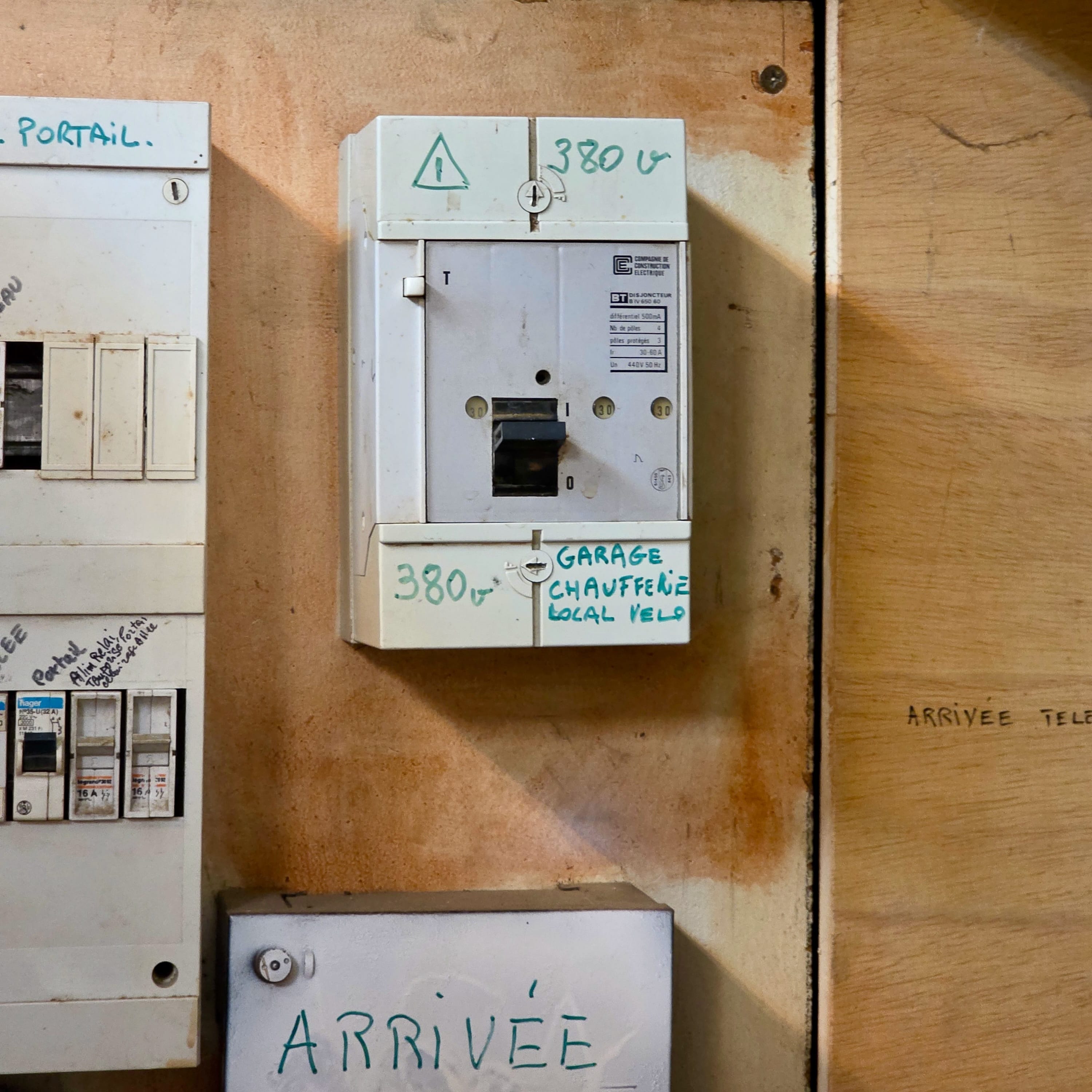 Ancien différentiel tétrapolaire CCE marqué 380 V avec bouton de test et manette, fixé sur une planche