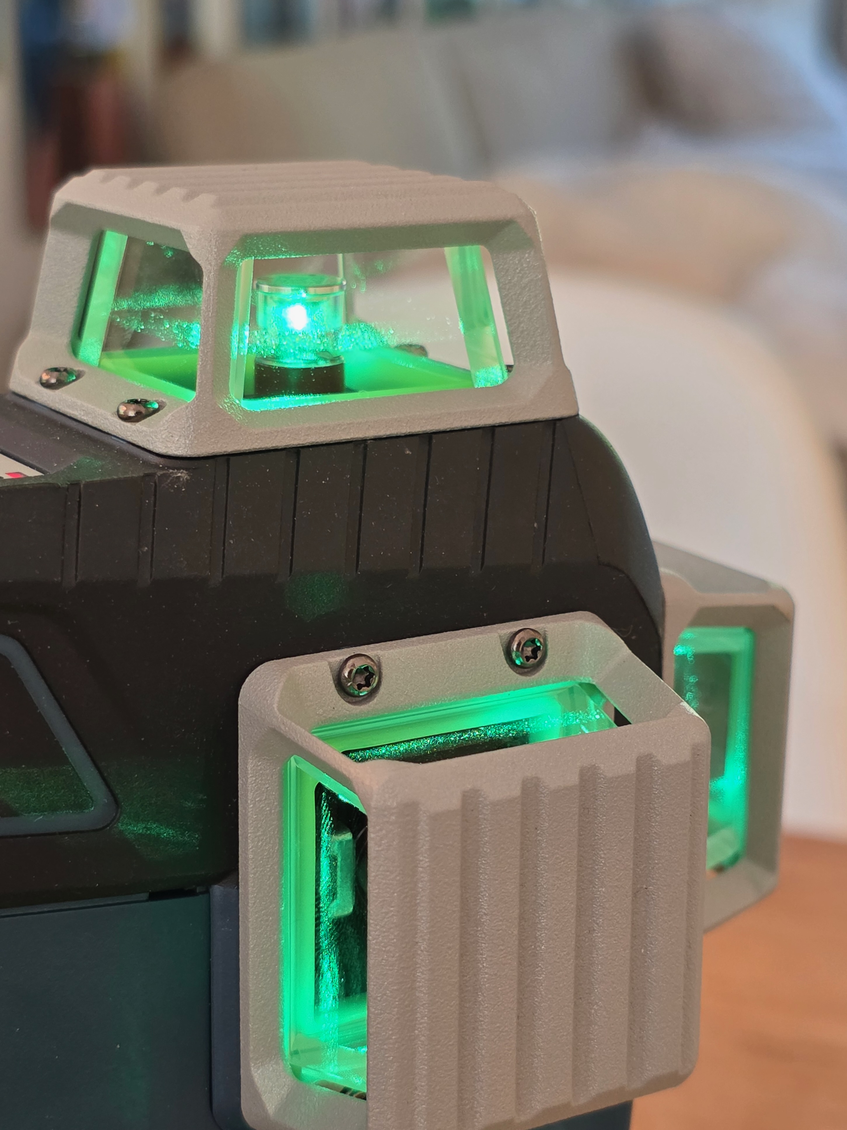Gros plan latéral d’un laser Bosch Professional vert allumé posé sur une table, fenêtres de sortie laser visibles sur le boîtier