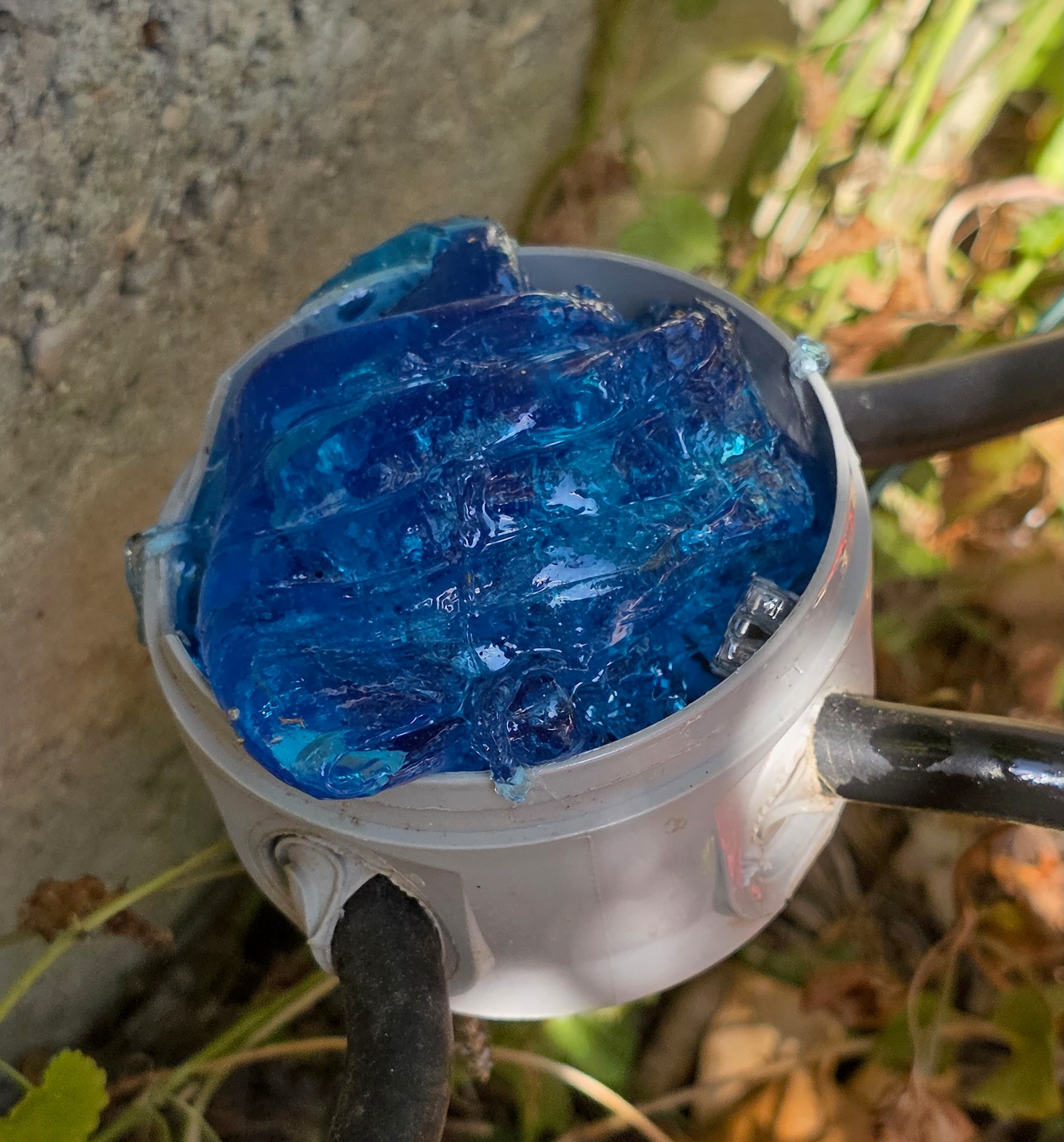 Boîte de dérivation ronde grise remplie de Magic Gel bleu vue de dessus, bornes entièrement noyées