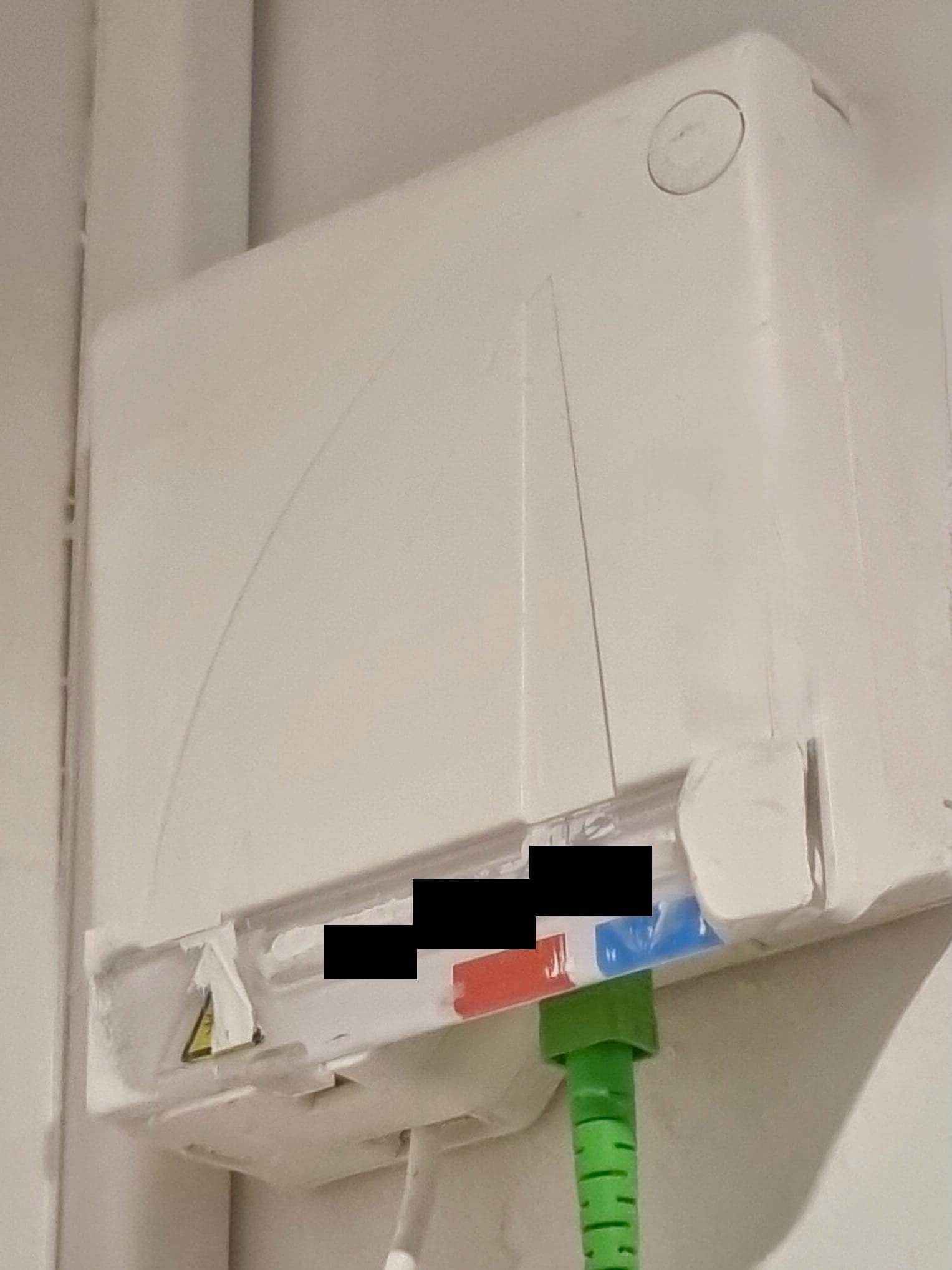 Boîtier d’arrivée fibre fixé au mur avec câble et connecteur verts