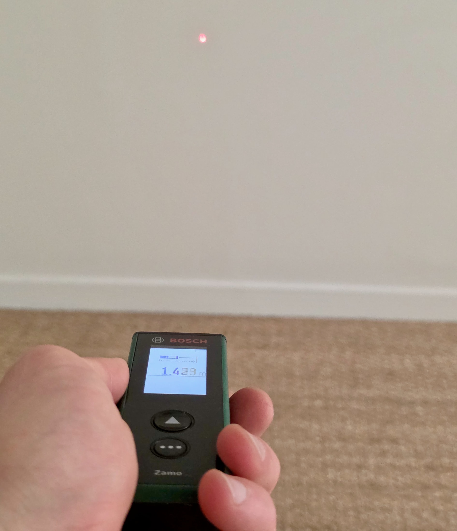 Télémètre laser Bosch Zamo posé contre un mur avec écran affichant une distance