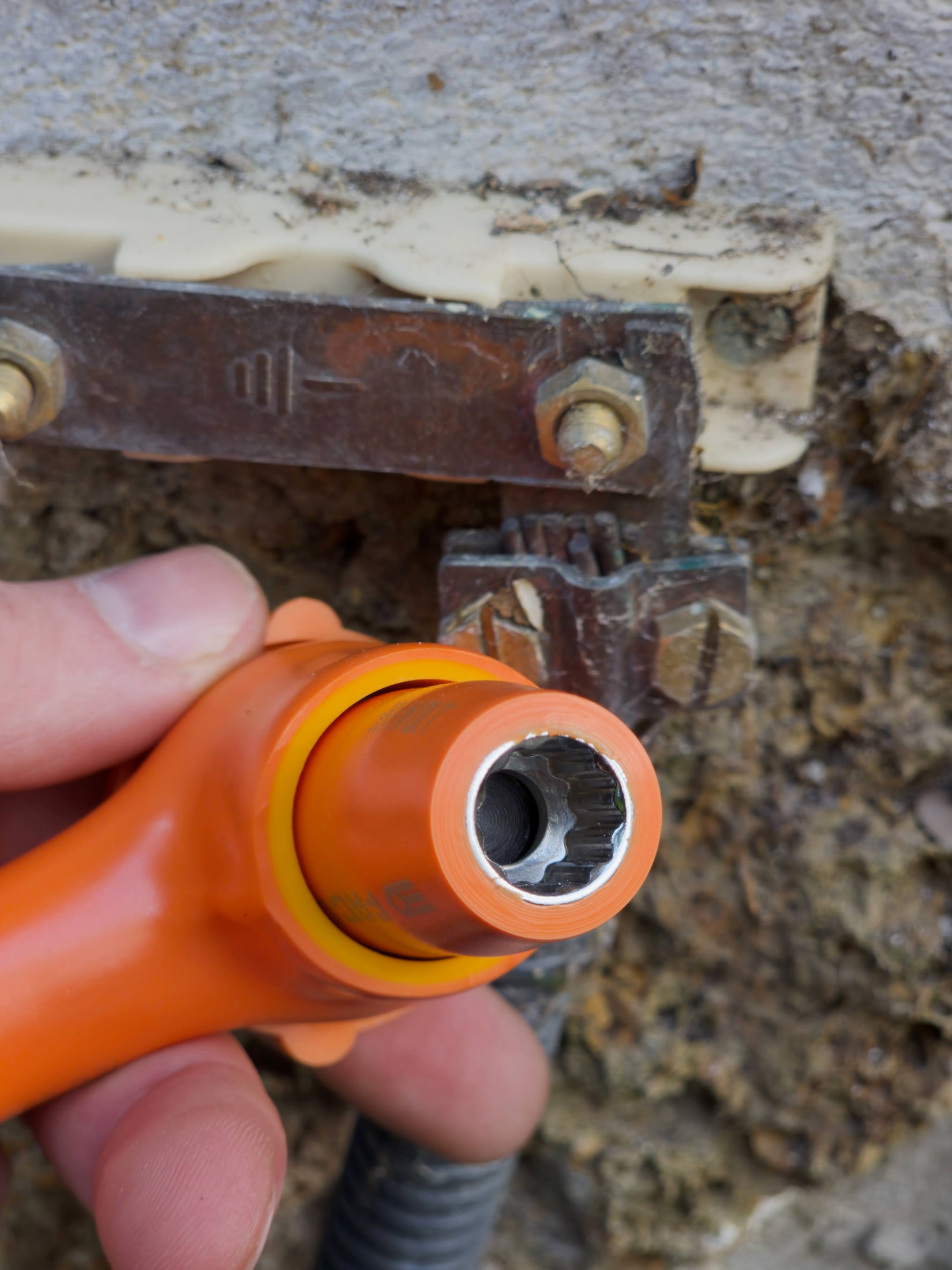 Cliquet FACOM isolé et douille de 10 mm sur la vis d’une barrette de terre