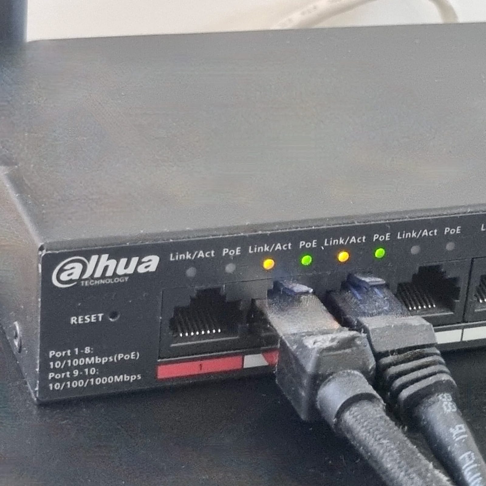 Gros plan sur la face avant d’un switch PoE avec deux câbles Ethernet branchés et des voyants Link et PoE allumés
