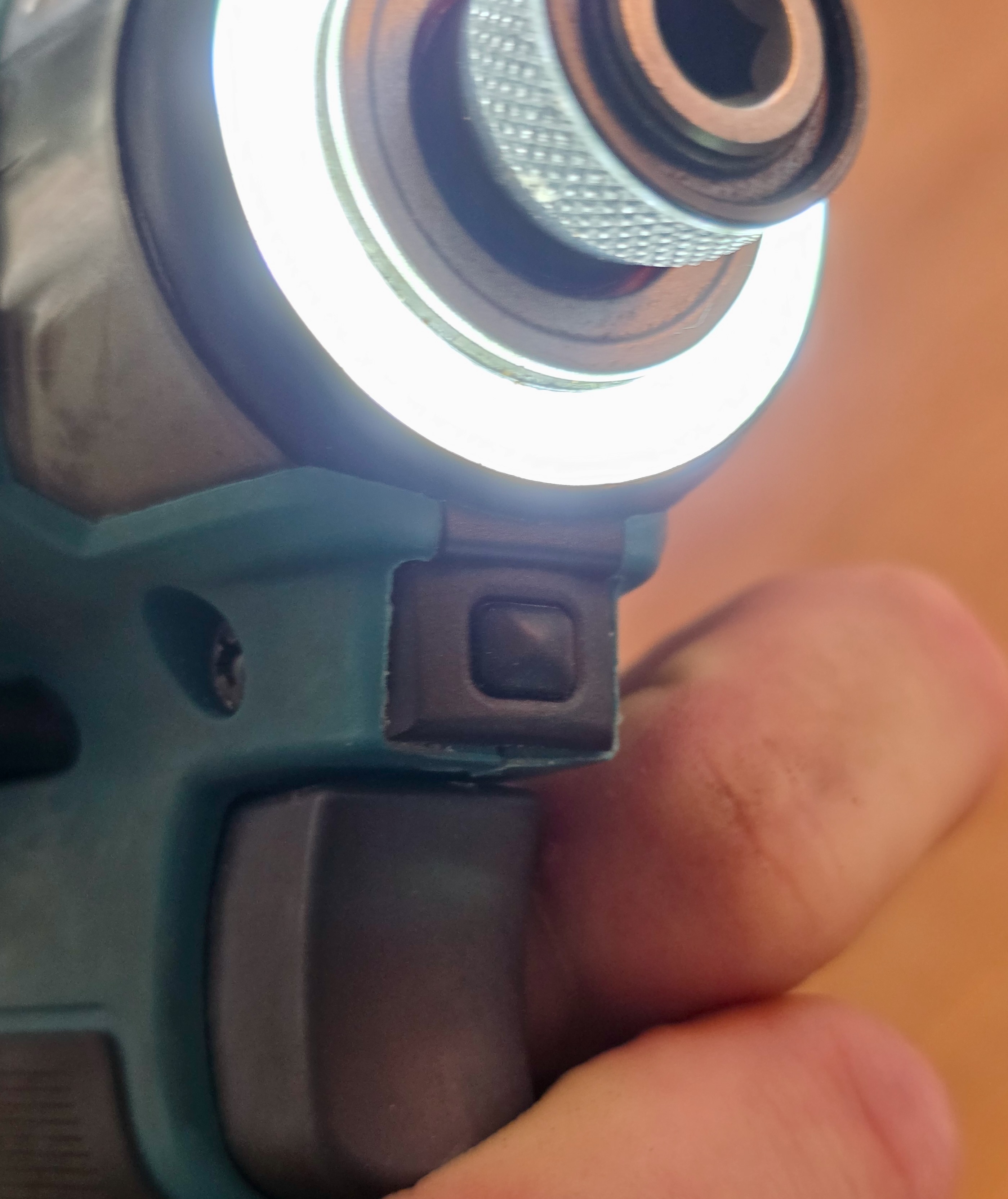 Doigt actionnant le bouton de changement de mode sur la tête de la visseuse Makita DT173