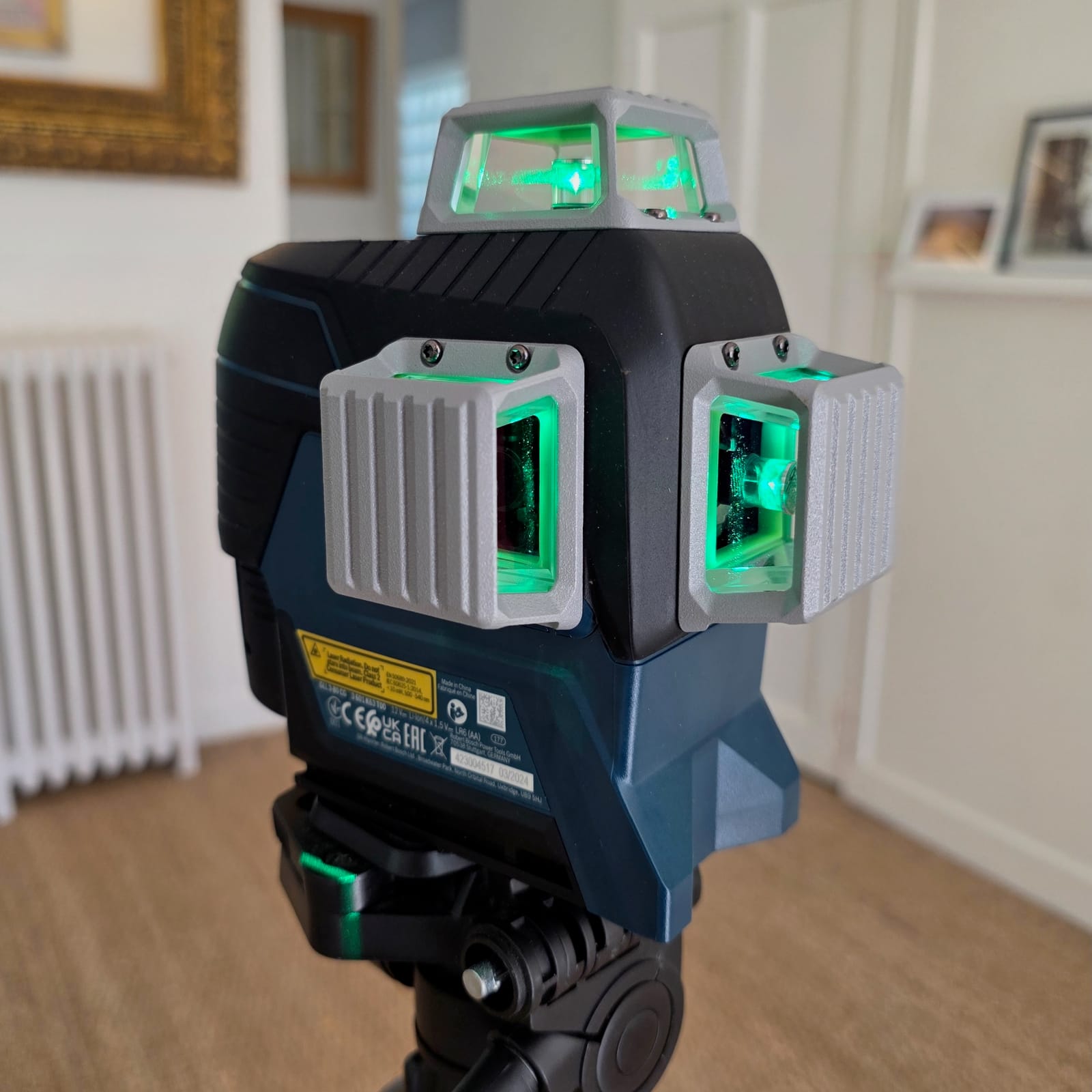 Gros plan d’un niveau laser Bosch GLL 3-80 CG allumé sur trépied, fenêtre d’émission supérieure visible