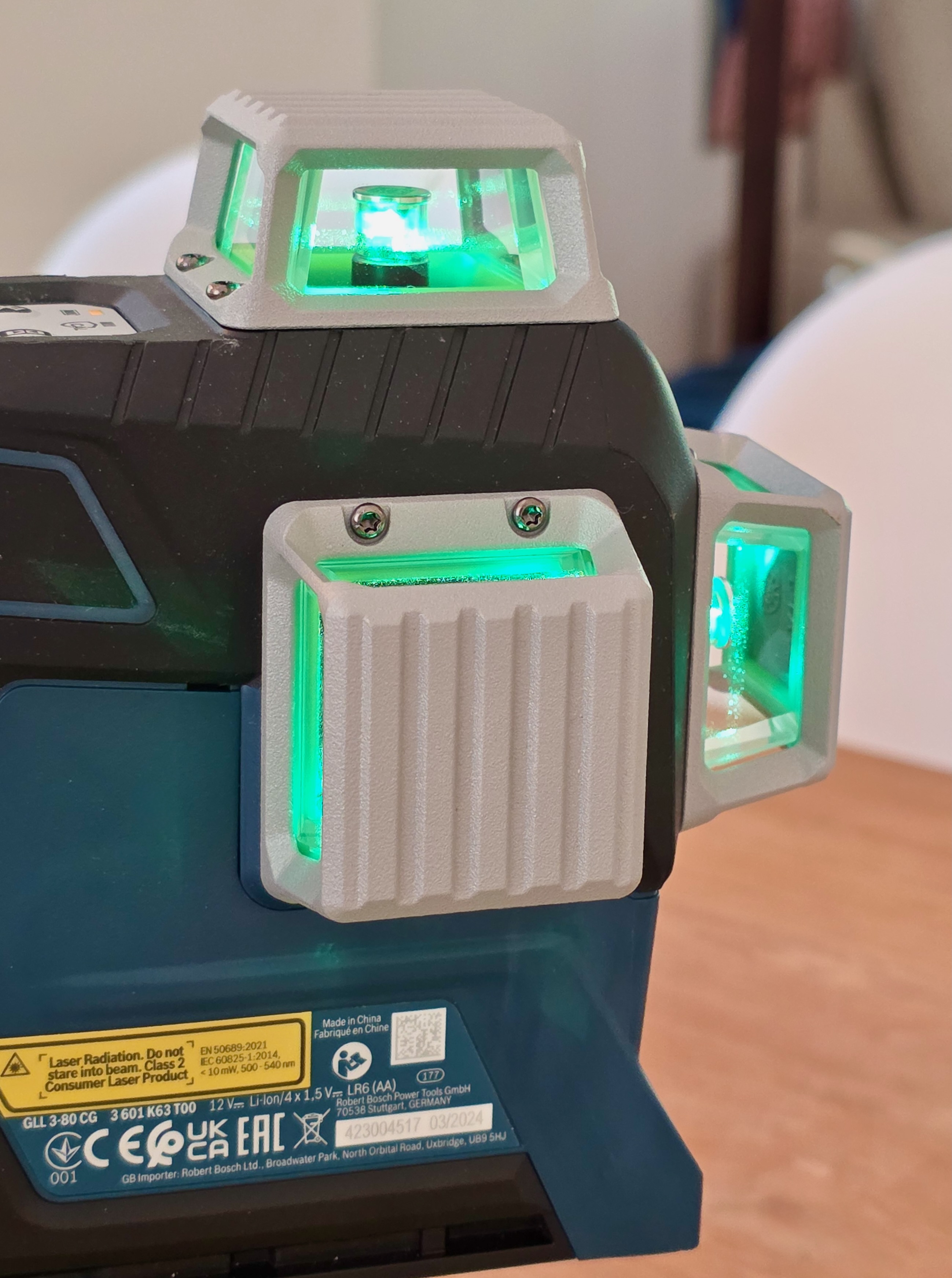 Gros plan latéral d’un niveau laser Bosch allumé sur une table, fenêtre d’émission du faisceau visible