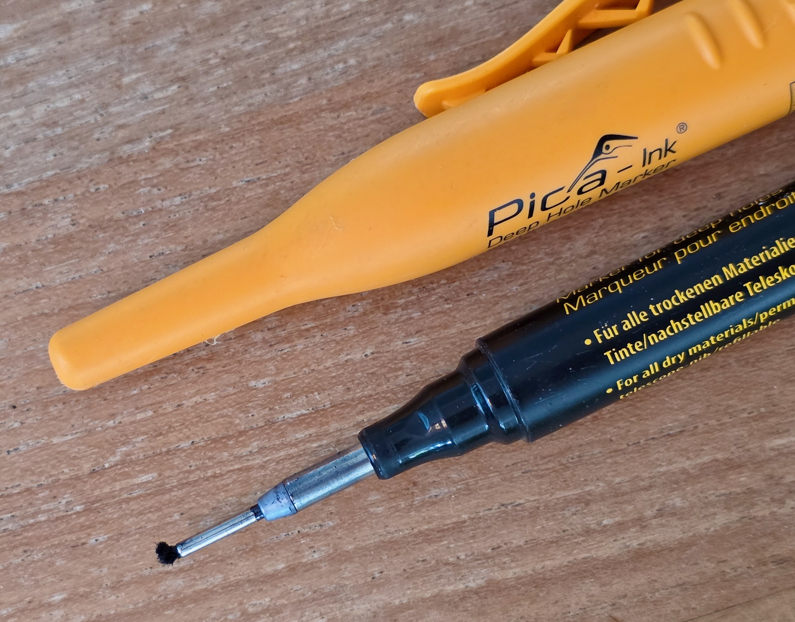 Marqueur Pica Ink ouvert, pointe télescopique déployée, posé à côté de son étui jaune