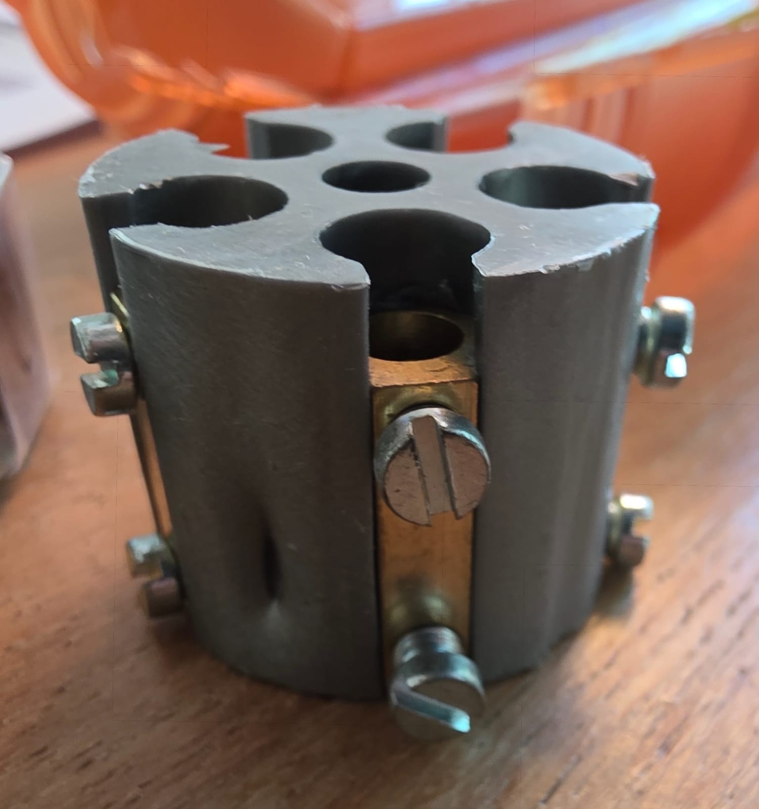 Gros plan sur un connecteur de jonction cylindrique gris à vis avec sa barre de cuivre