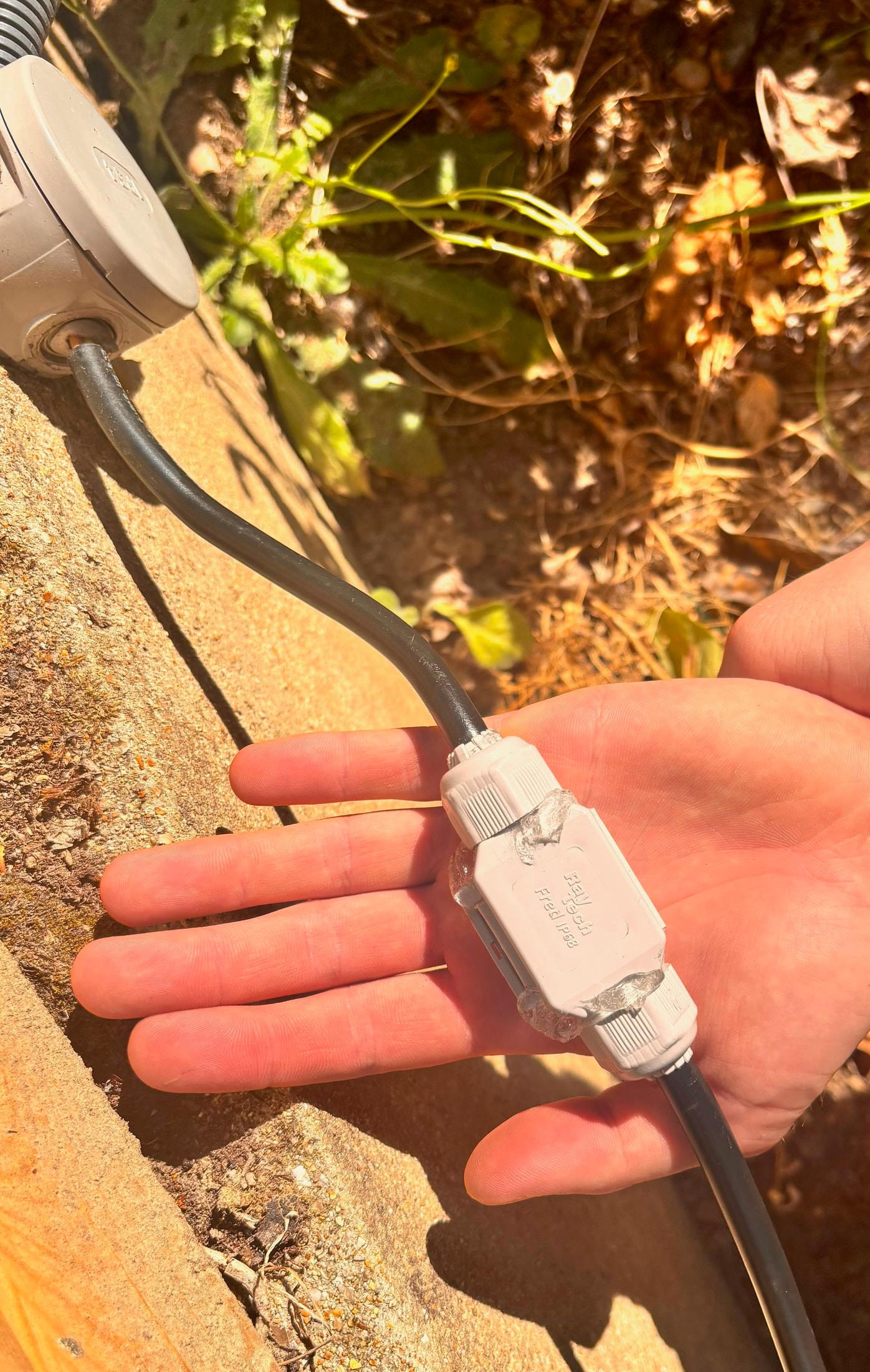 Connecteur Raytech Fred IP68 tenu dans la main, fermé avec un domino connecté dedans, le gel dépasse légèrement sur les bords