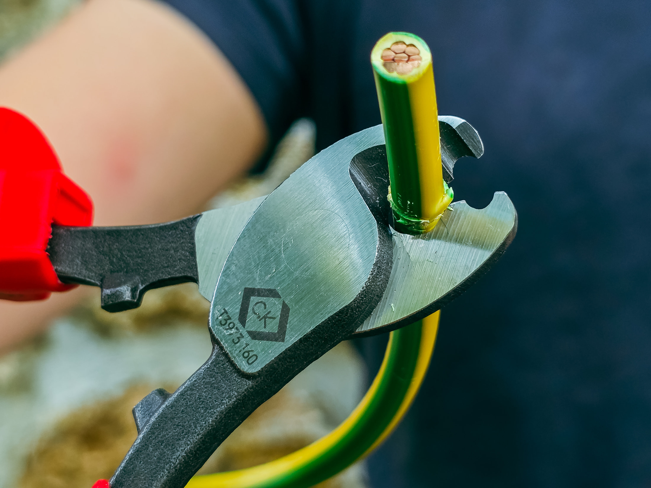 Nahaufnahme des C.K Tools-Kabelschneiders T3973-160 an einem grün-gelben Leiter