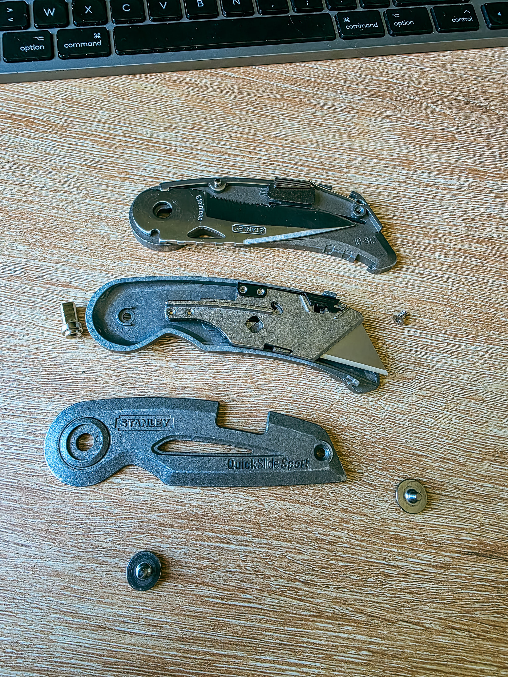 Cutter Stanley QuickSlide Sport volontairement démonté, avec ses pièces séparées sur un bureau en bois