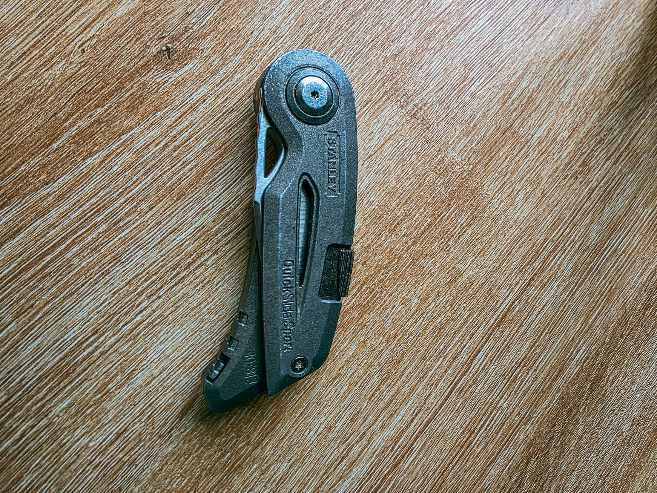 Cutter Stanley QuickSlide Sport fermé, posé sur une surface en bois