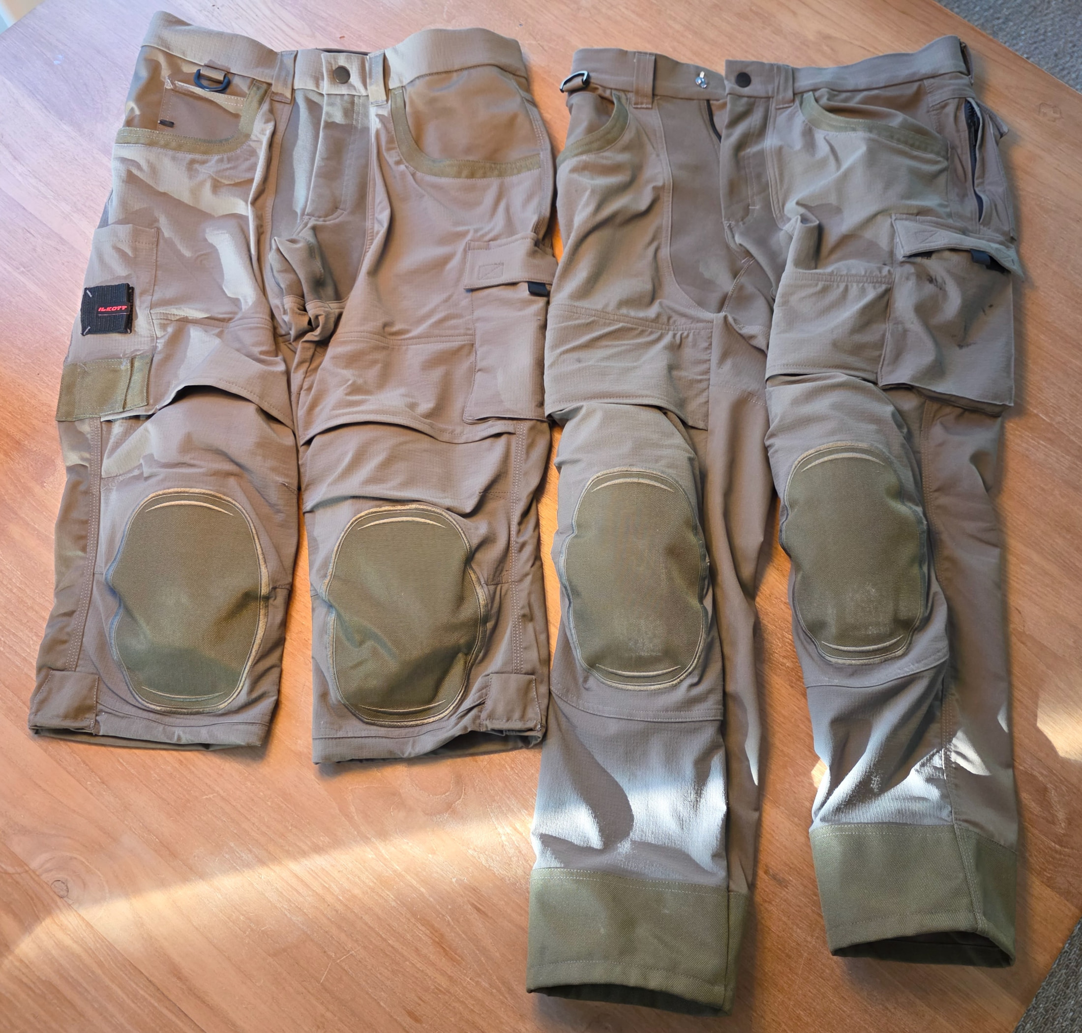 Zwei Arbeitshosen Ilkott mit integrierten Knieschonern und mehreren Taschen auf einem hellen Holztisch