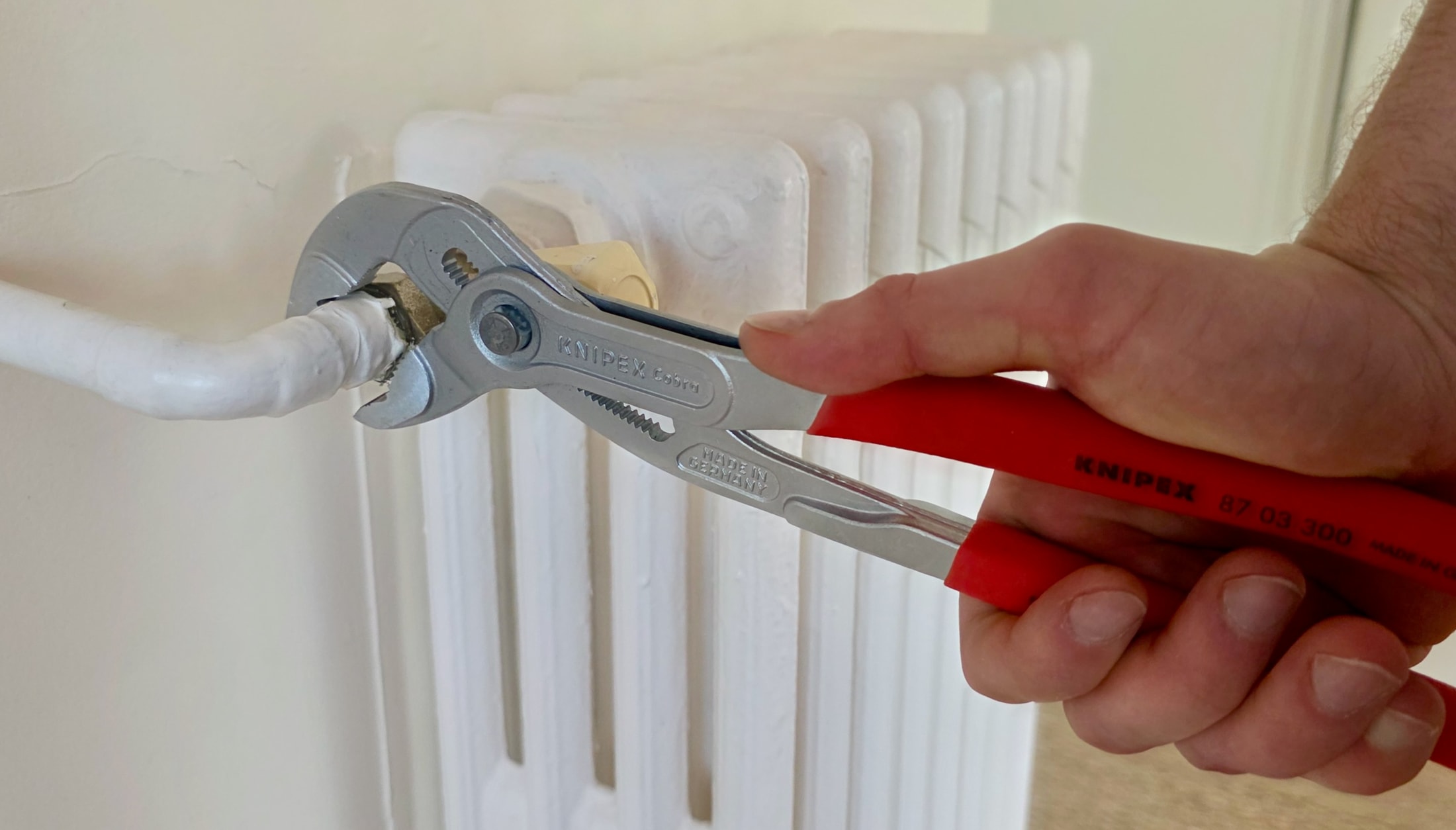 Pince multiprise KNIPEX en train de dévisser un écrou de radiateur
