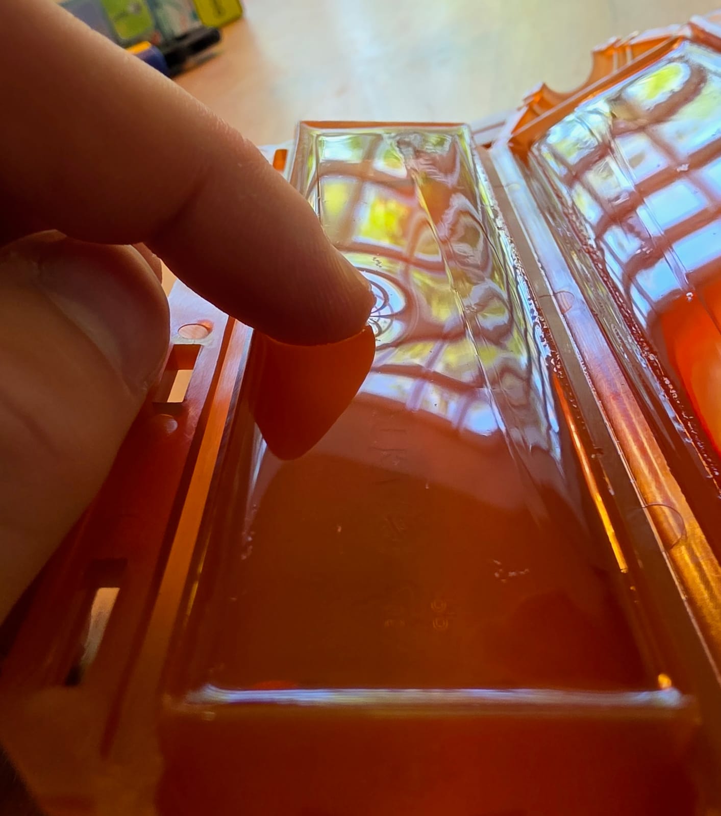 Doigt touchant la résine gel à l’intérieur d’une coque orange Ready Cast, gros plan