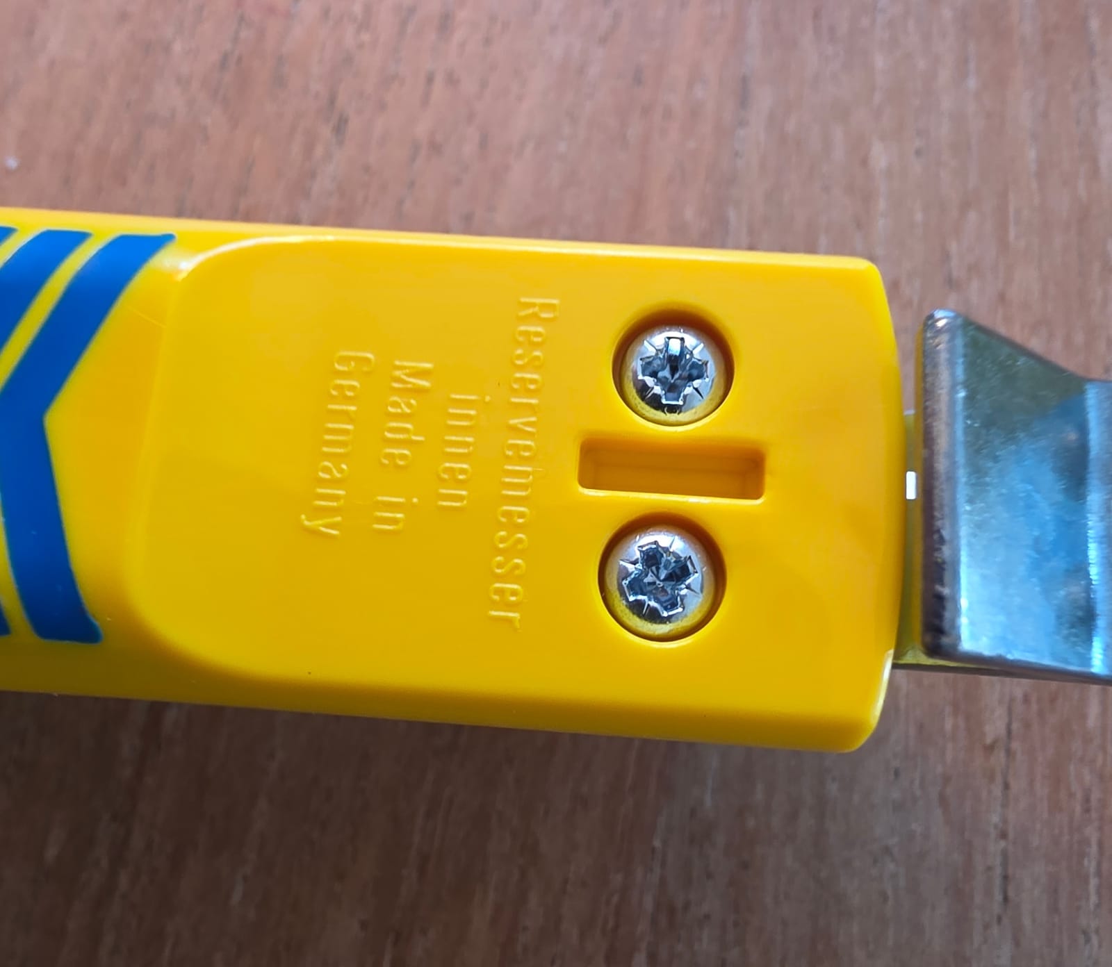 Dos de la poignée jaune du dénudeur Jokari avec l’inscription Reservemesser innen et deux vis