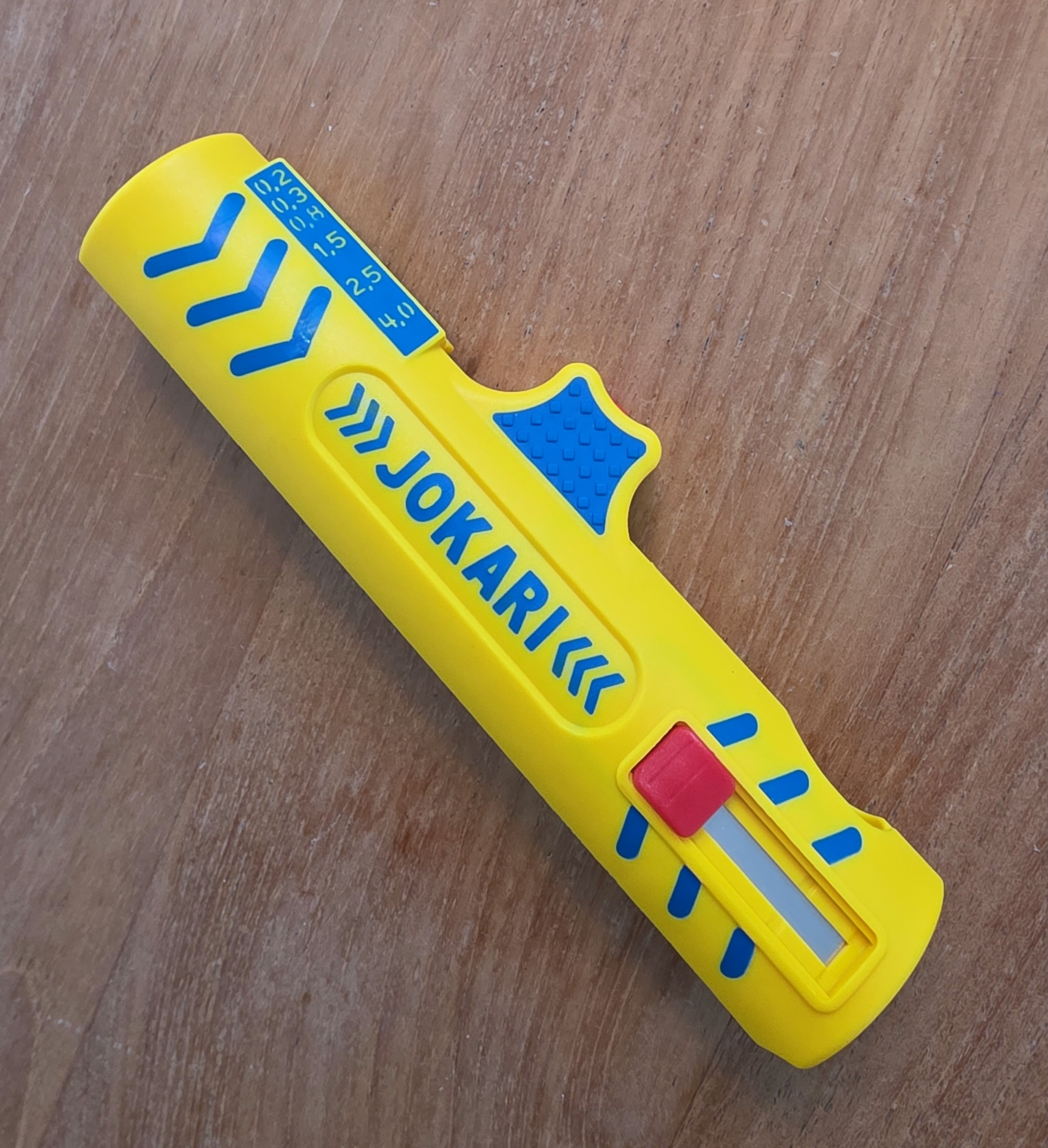 Face avant du dénudeur Jokari Secura No. 15 jaune et bleu, logo JOKARI, bouton rouge et graduations des sections de fils