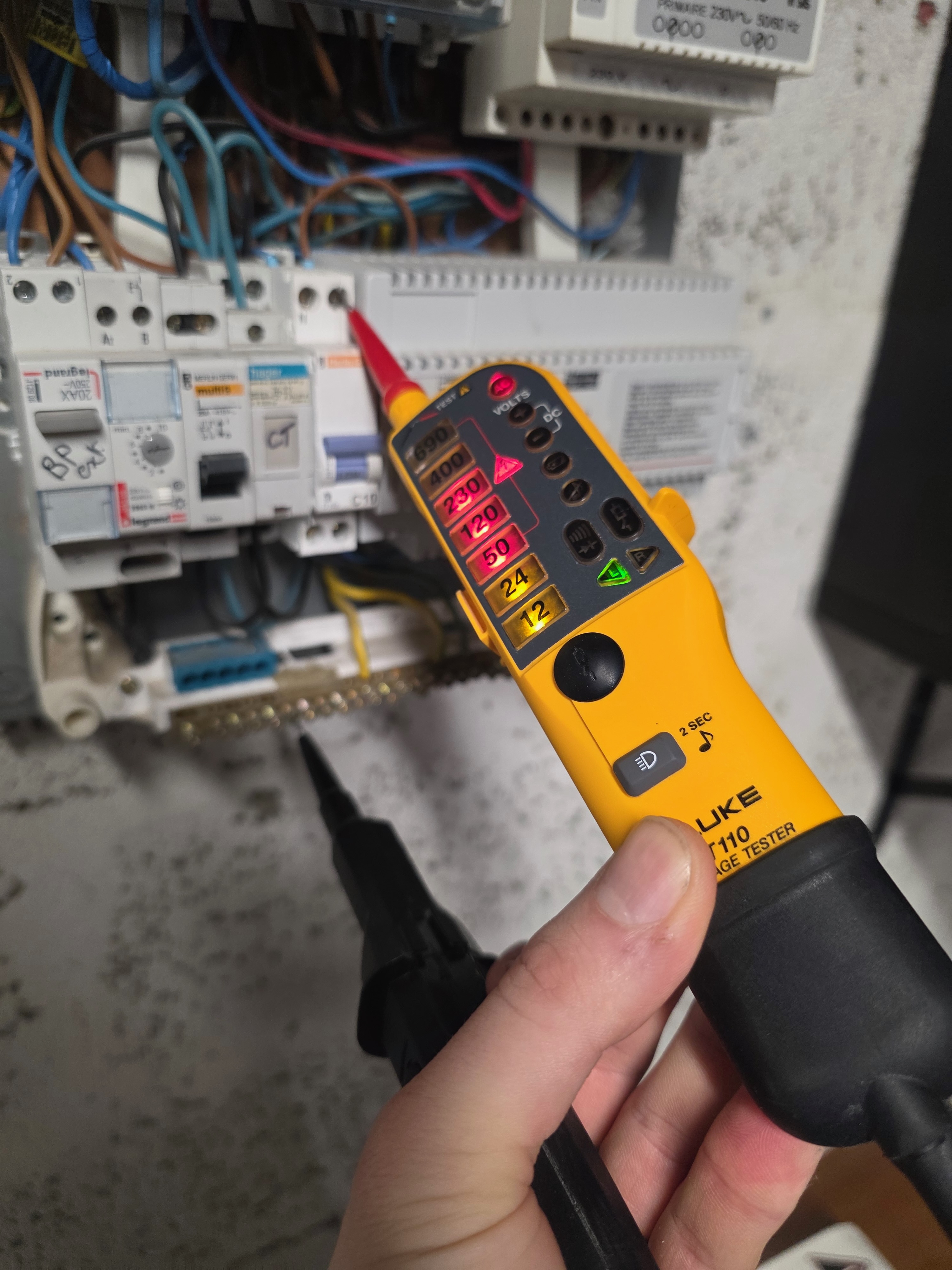 Fluke T110 bipolaire devant un tableau électrique ouvert, LED 230 V allumée