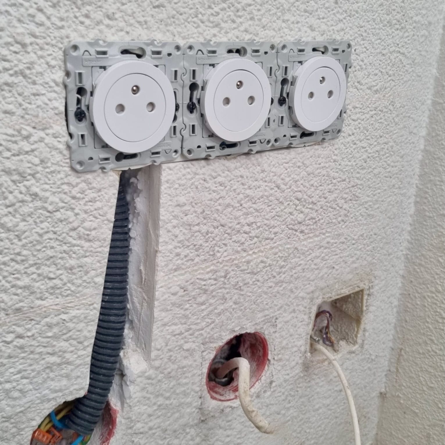 Installation d'une prise Odace encastrée sur mur de chantier