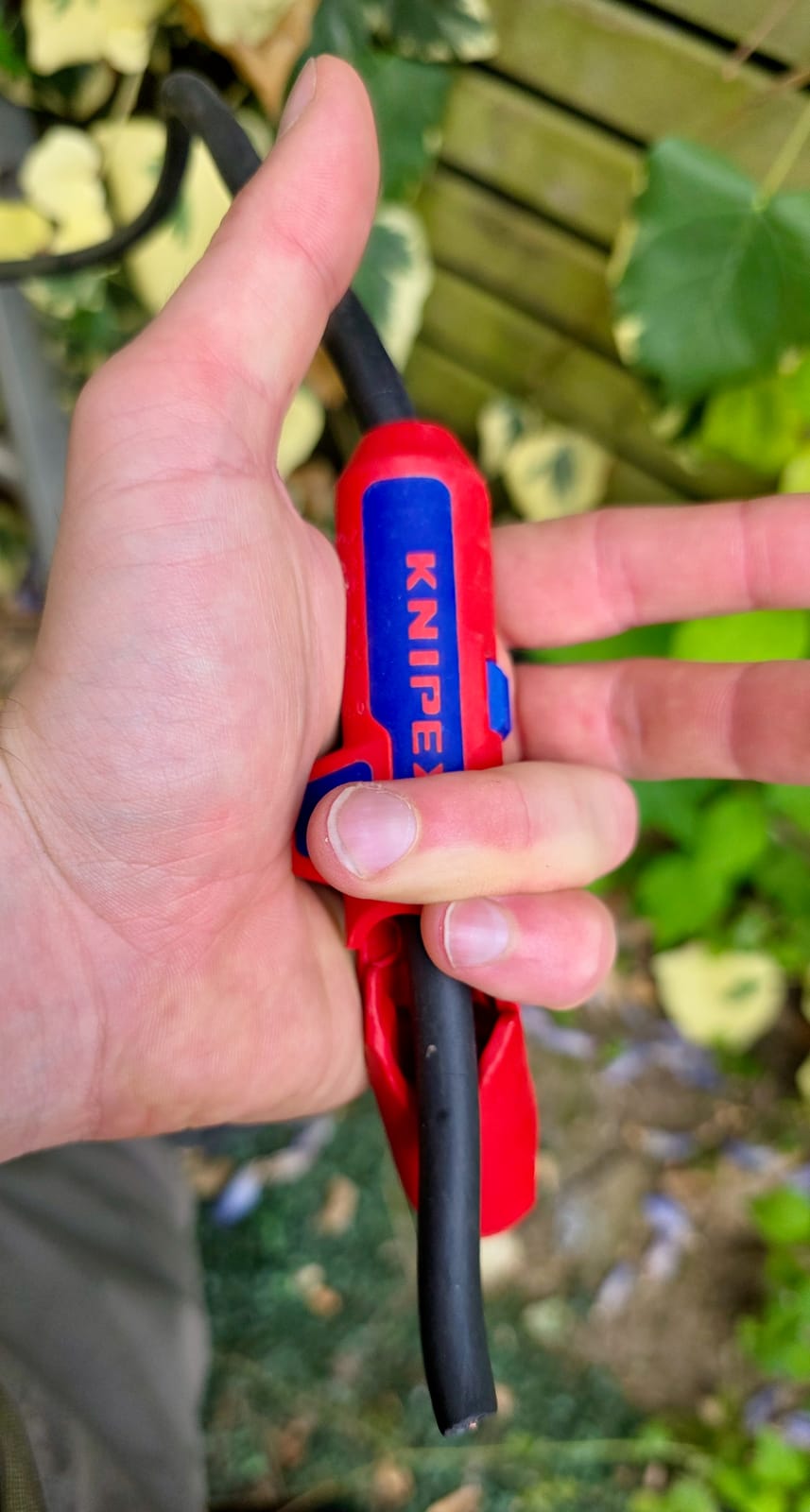 Knipex ErgoStrip tenu en main avec un câble R2V engagé en cours de dénudage