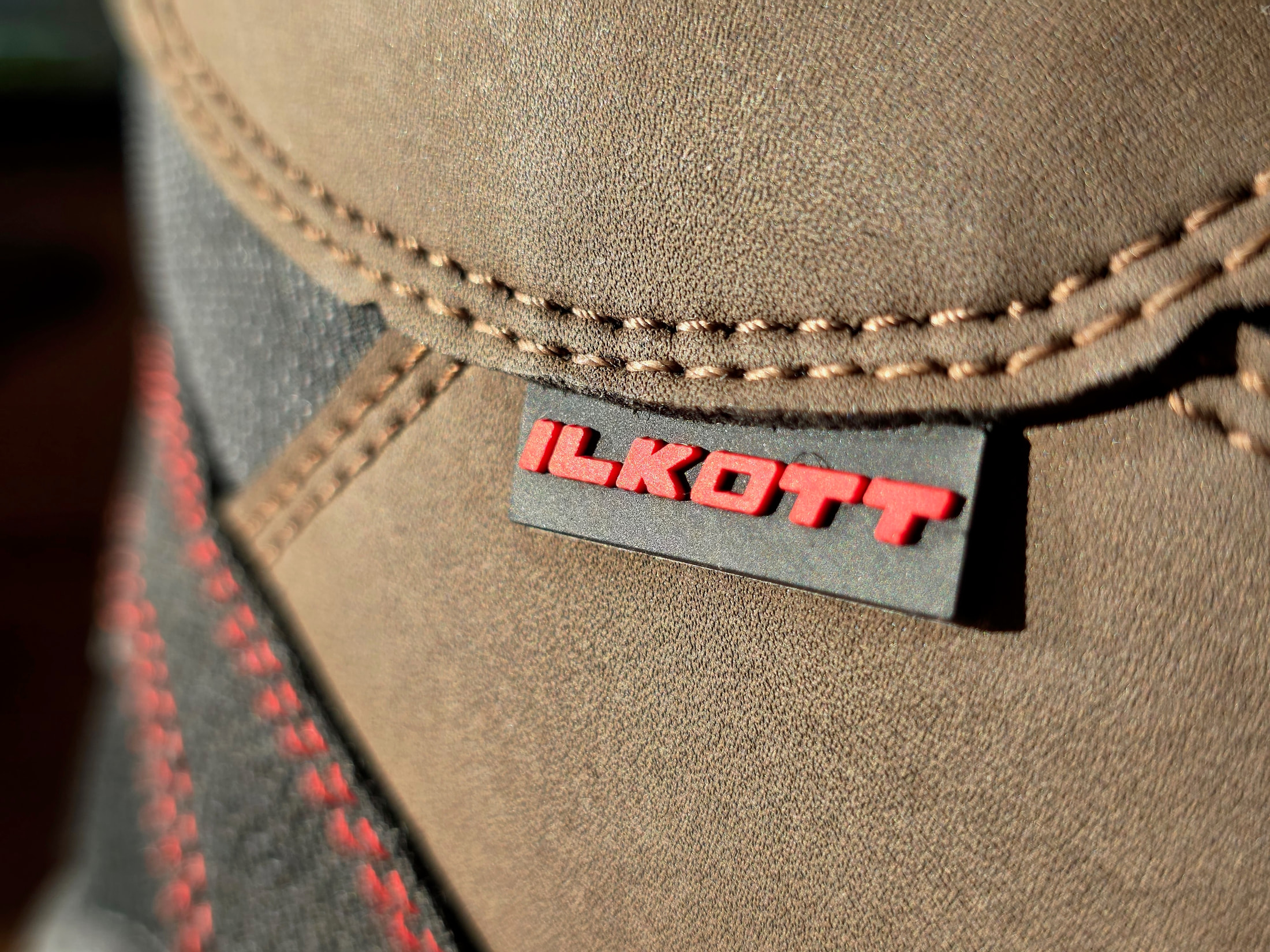 Logo Ilkott rouge sur étiquette noire cousue sur une chaussure en daim marron
