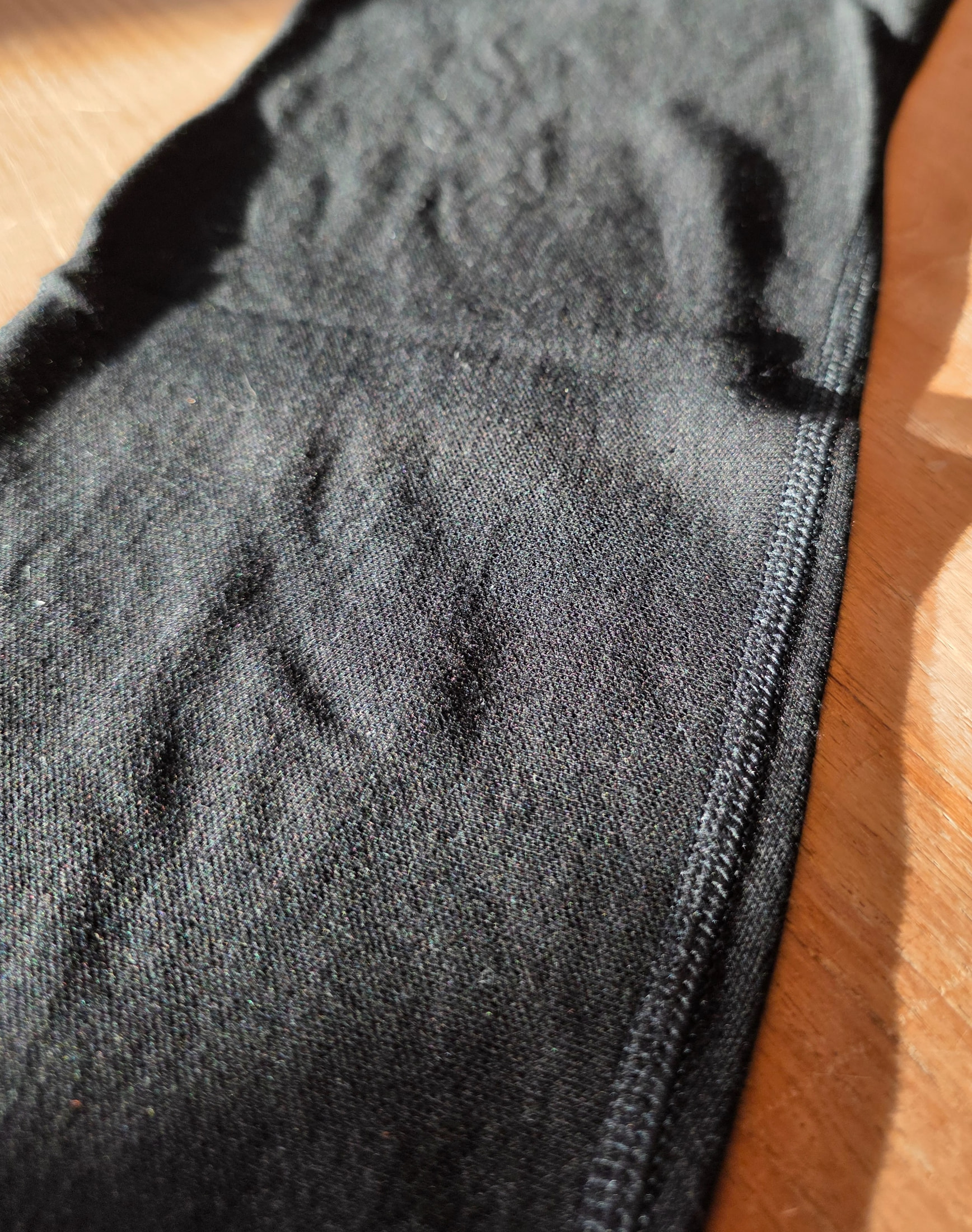 Macro de la couture surjet de la maille noire du caleçon thermique Ilkott ZZ17 sur un fond de bois clair