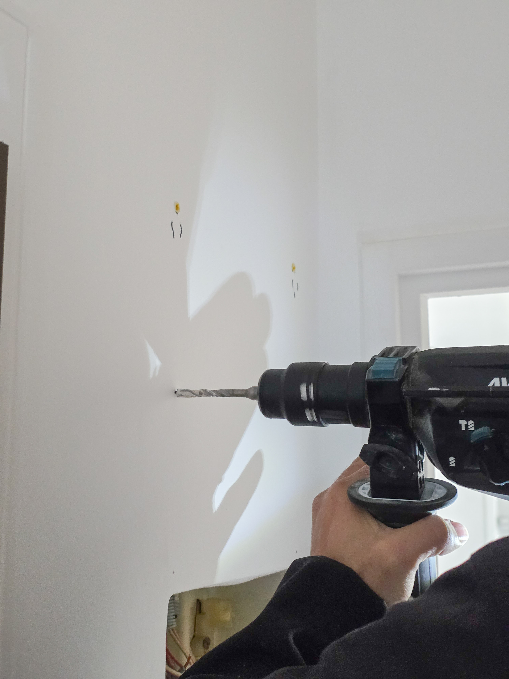 Perforateur Makita DHR283 en train de percer un mur blanc, gros plan