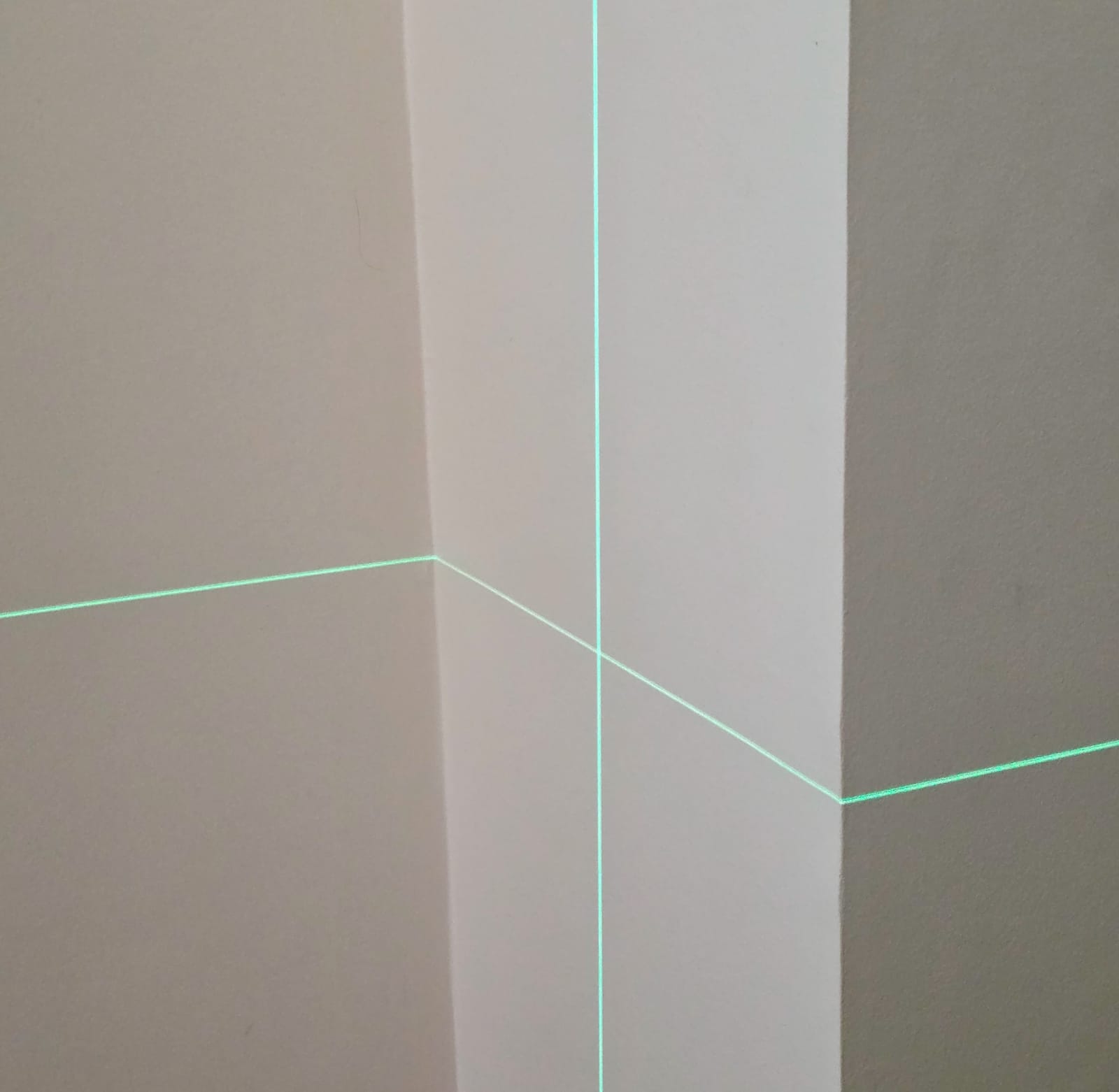 Lignes laser vertes projetées sur un mur blanc lors d’un essai de nivellement