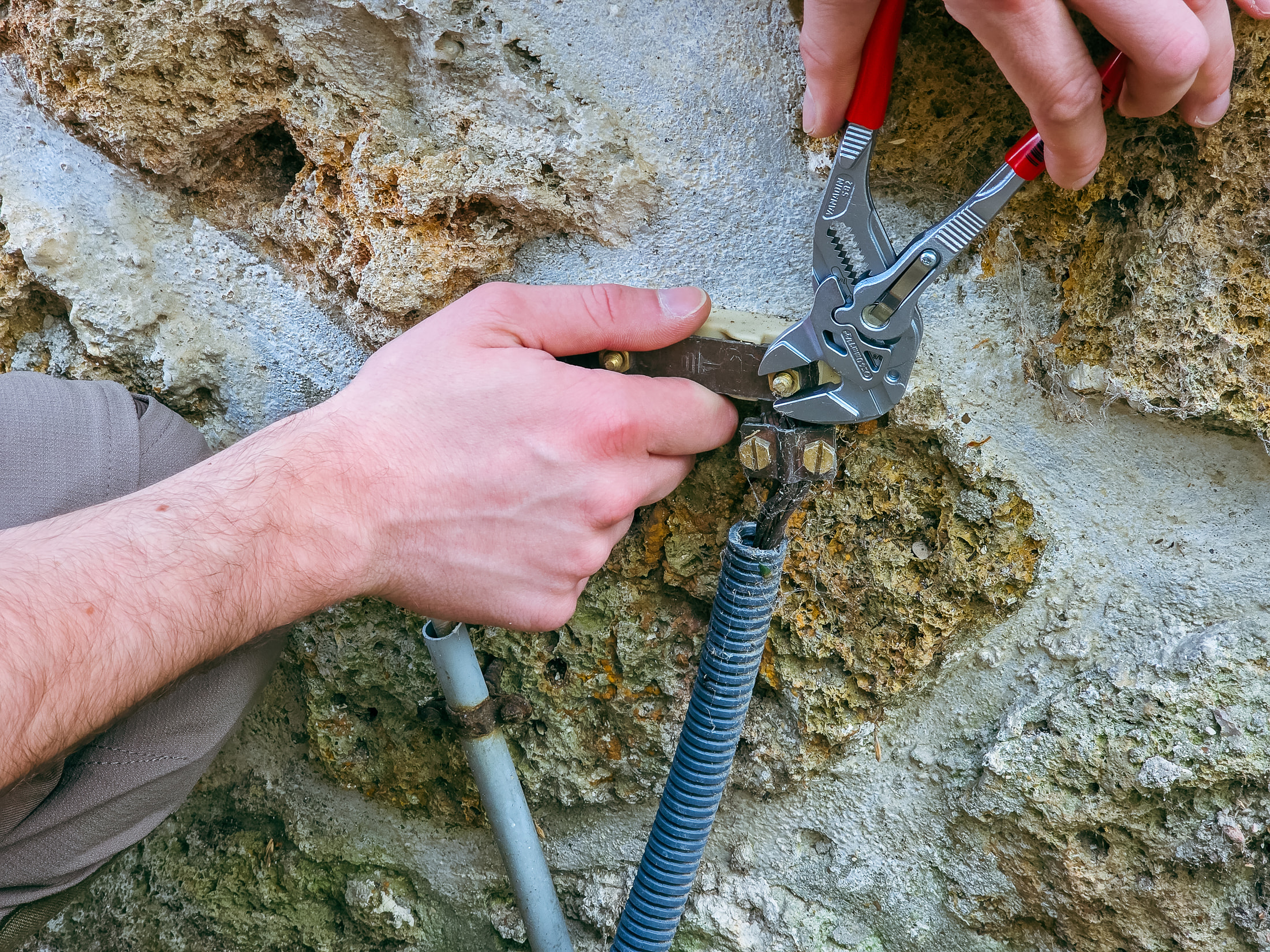 Gros plan des mâchoires lisses d’une pince-clé Knipex 86 02 180 sur le boulon d’une barrette de terre