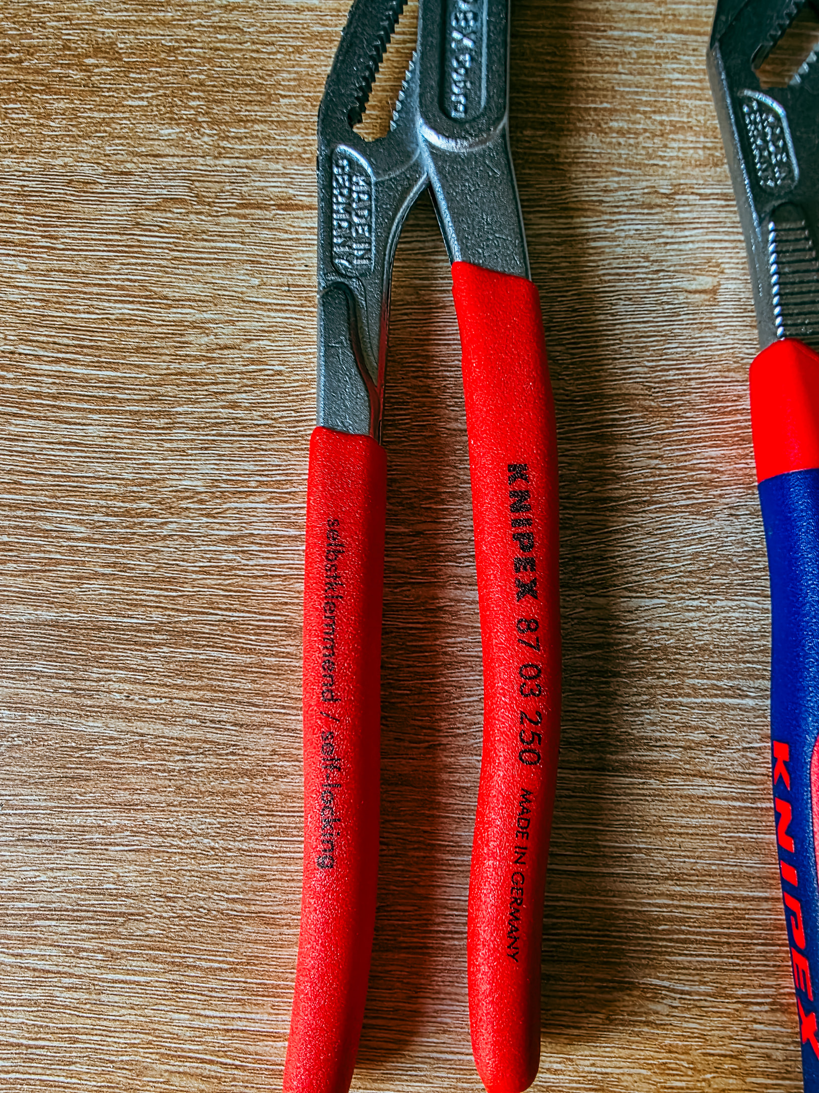 Pince multiprise Knipex Cobra 87 03 250 à manche rouge, marquage visible, posée sur du bois
