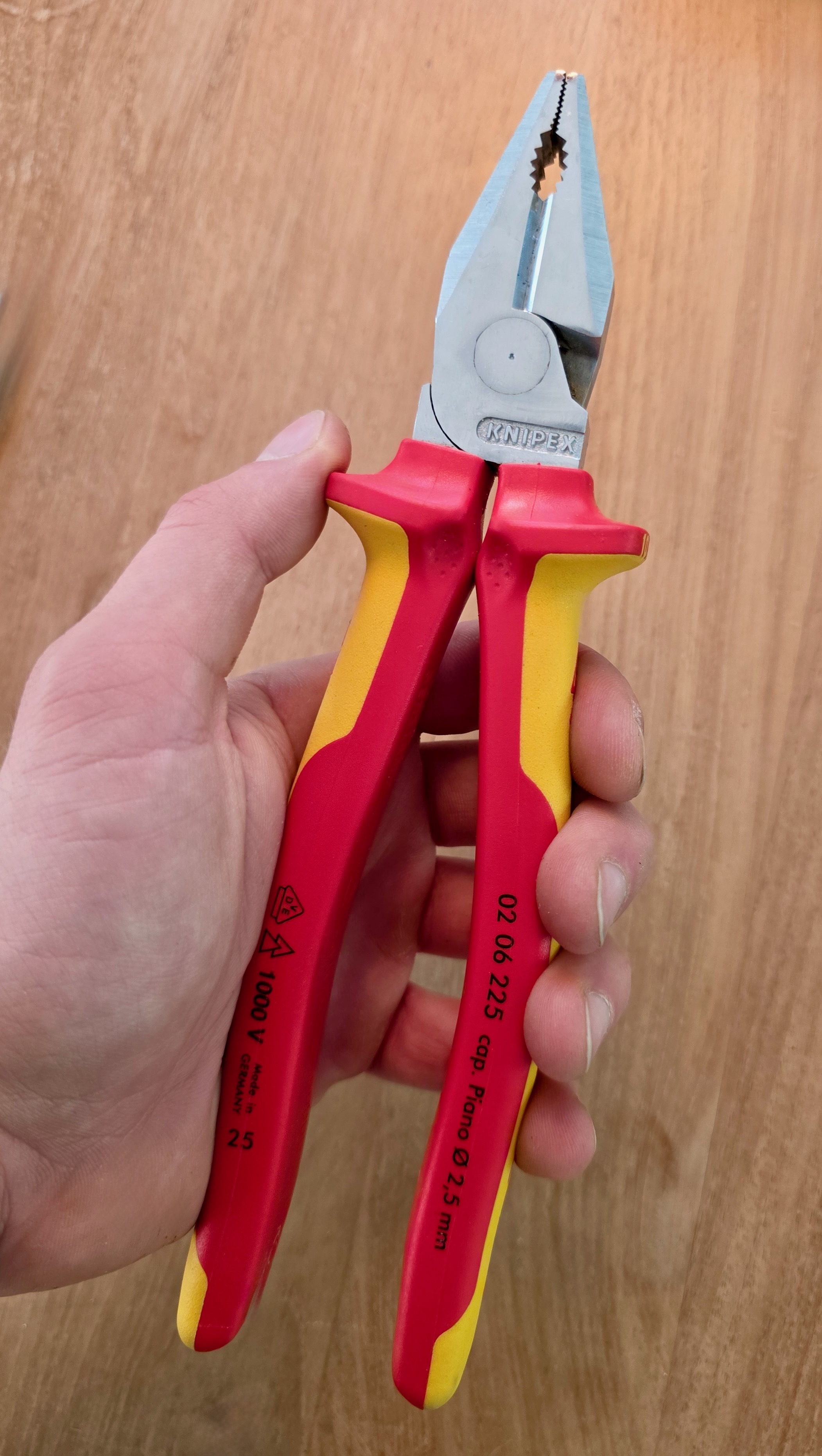 Pince universelle VDE Knipex 02 06 225 tenue en main, symbole 1000 V imprimé sur la poignée jaune