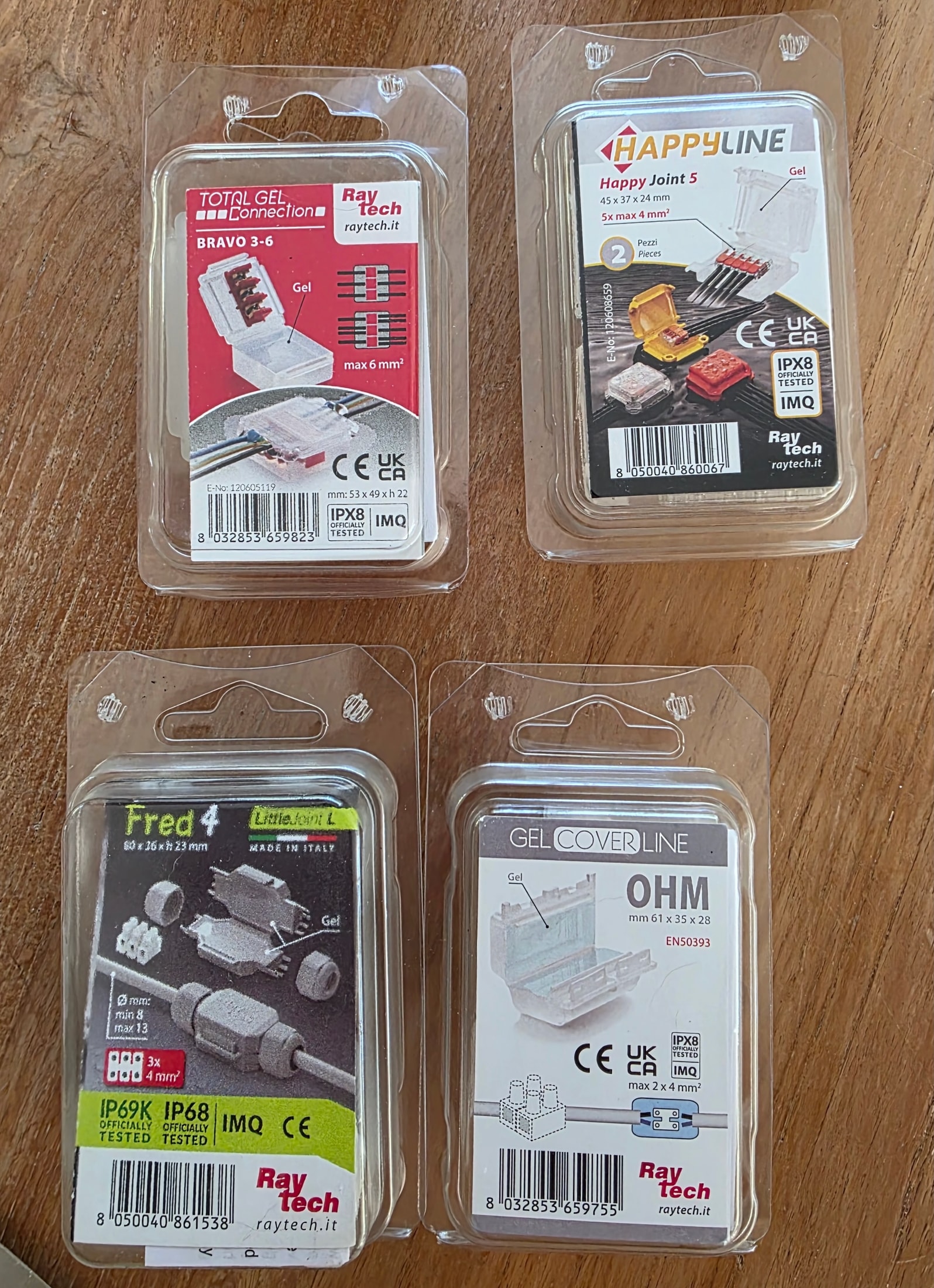 Quatre emballages de connecteurs étanches Raytech Bravo, Happy Joint, Fred et Ohm posés sur du bois