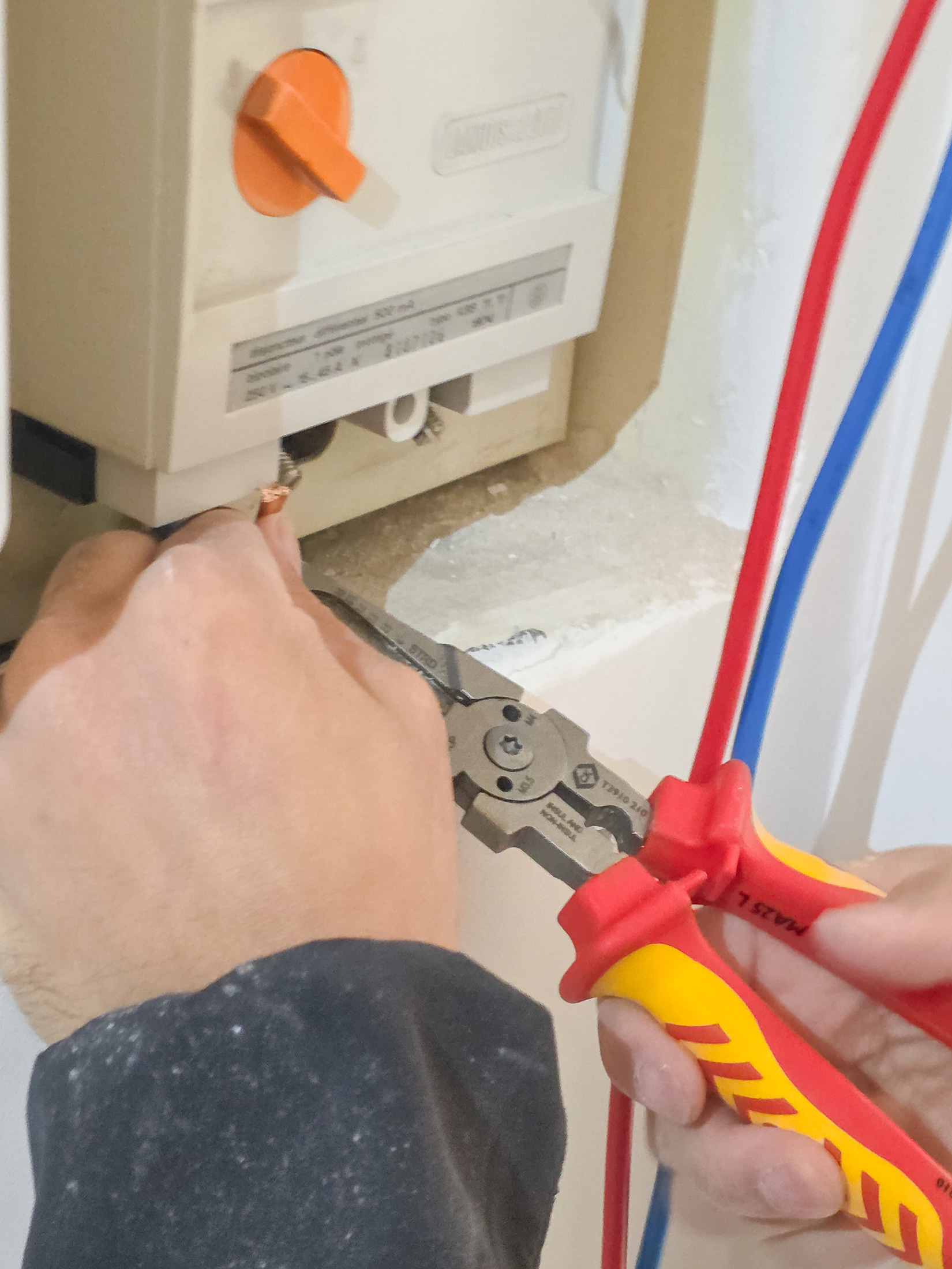 Pinza multifunción C.K Tools junto a conductores rojos y azules en una caja eléctrica