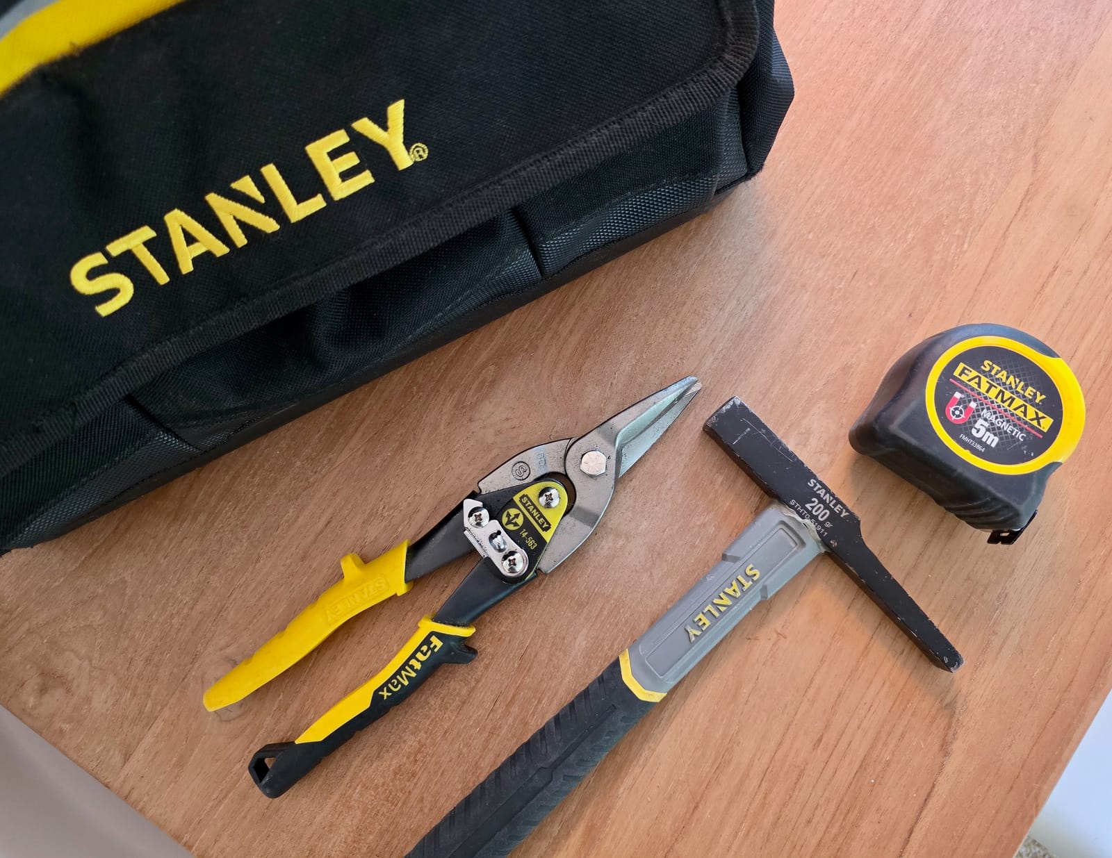 Sacoche Stanley ouverte avec outillage posé sur une table en bois