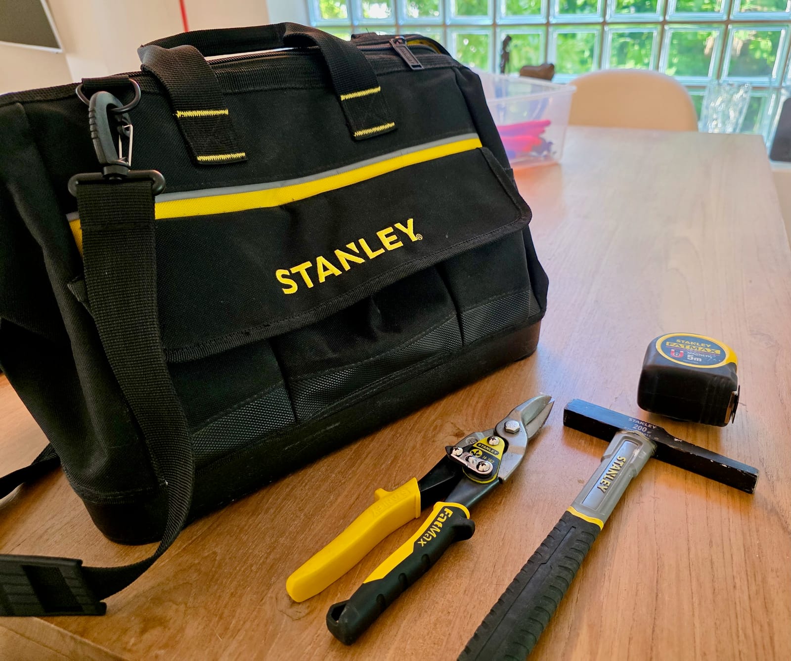 Sac Stanley avec marteau d’électricien, pince coupante FatMax et mètre FatMax magnétique sur une table en bois