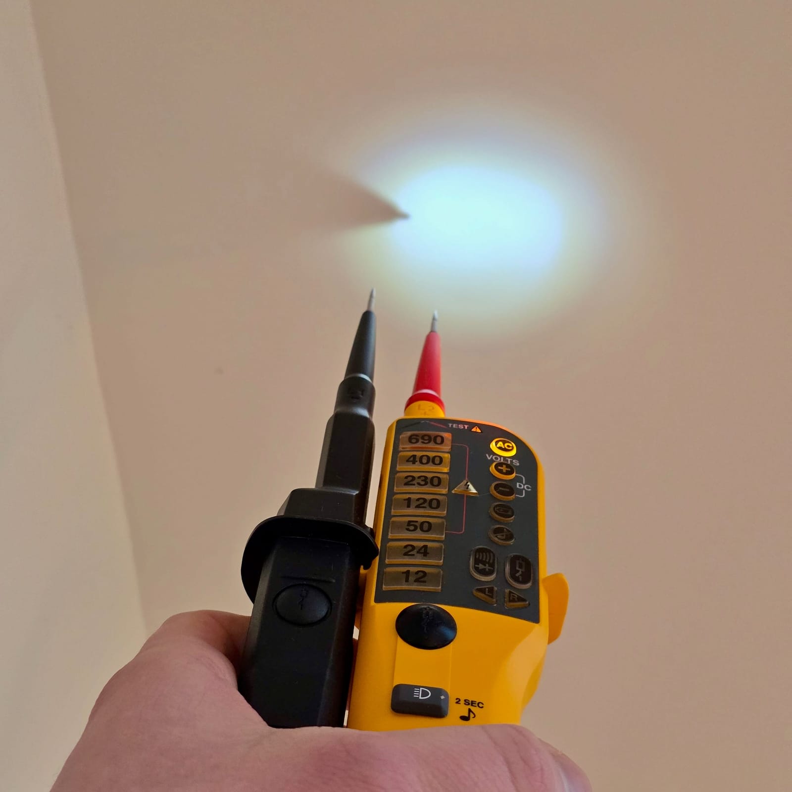 Vérificateur d’absence de tension Fluke T110 posé près d’un mur blanc