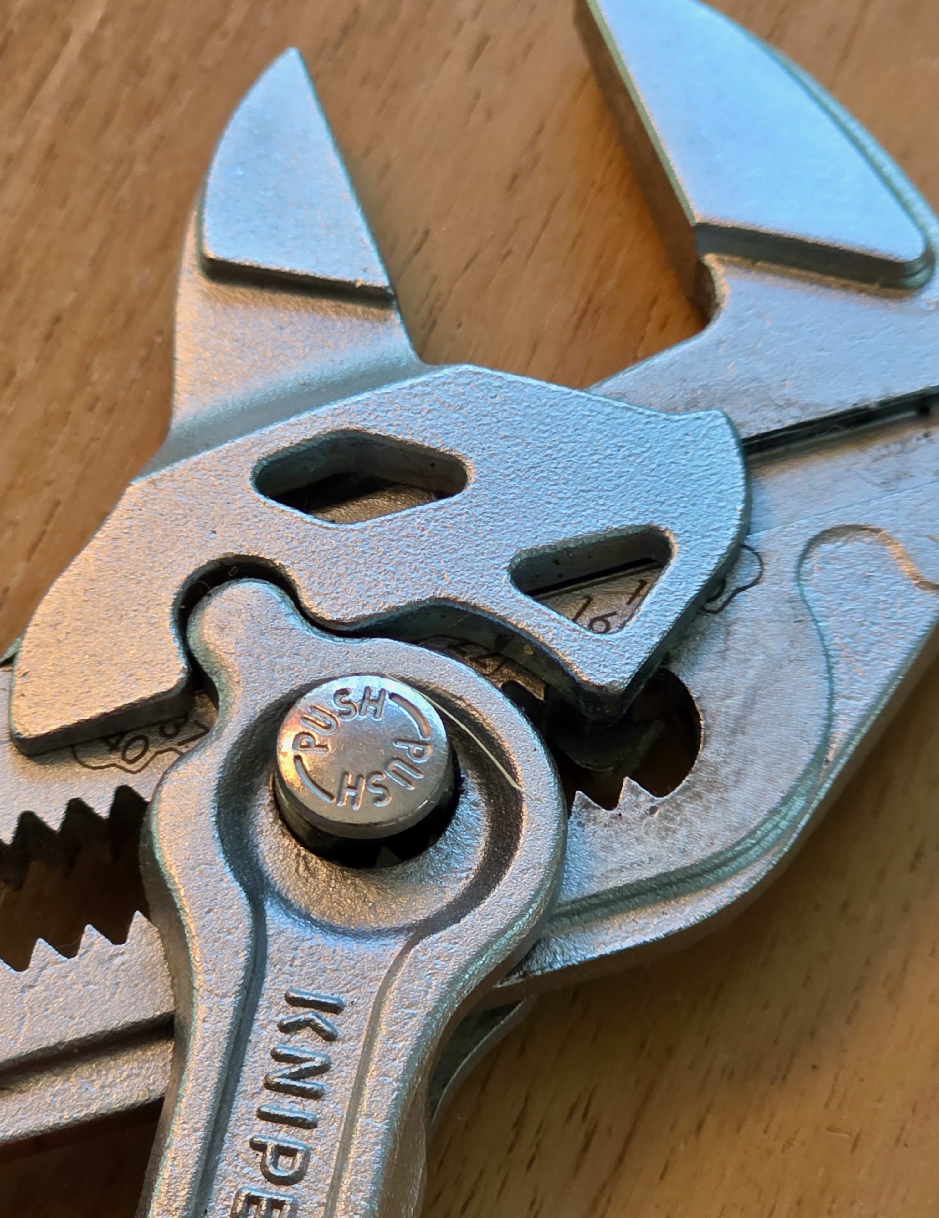 Gros plan sur la mâchoire lisse et le bouton PUSH d’une pince-clé Knipex de format poche