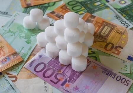 Pastilles de sel pour adoucisseur posées sur des billets de banque, illustrant le coût annuel du sel
