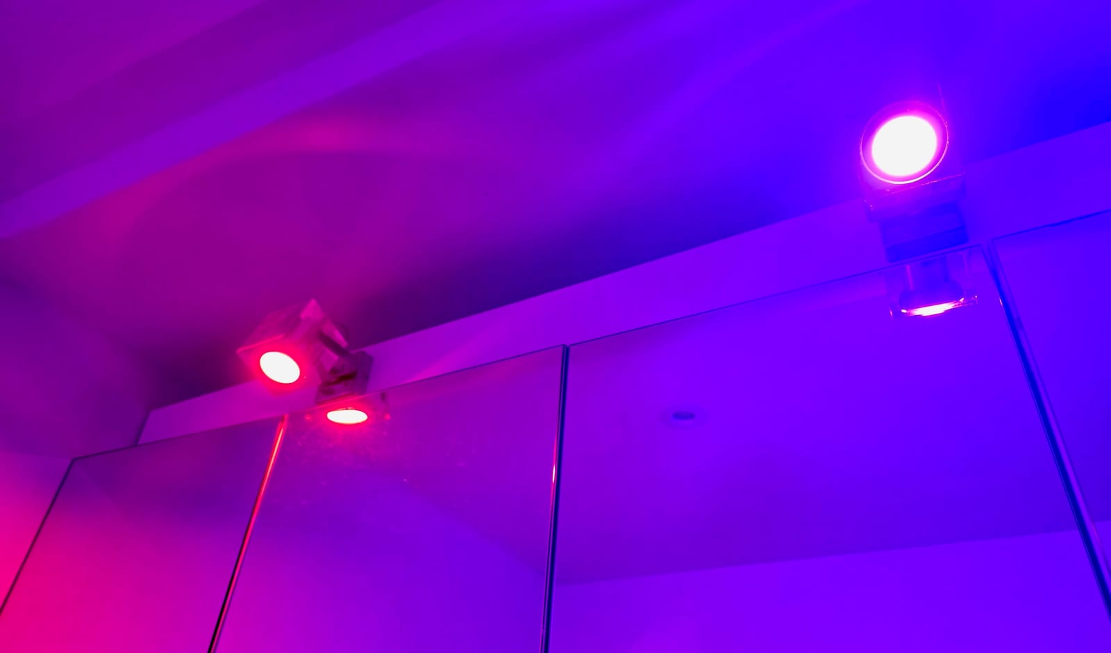 Deux spots Philips Hue GU10 allumés en violet et rose au-dessus de miroirs