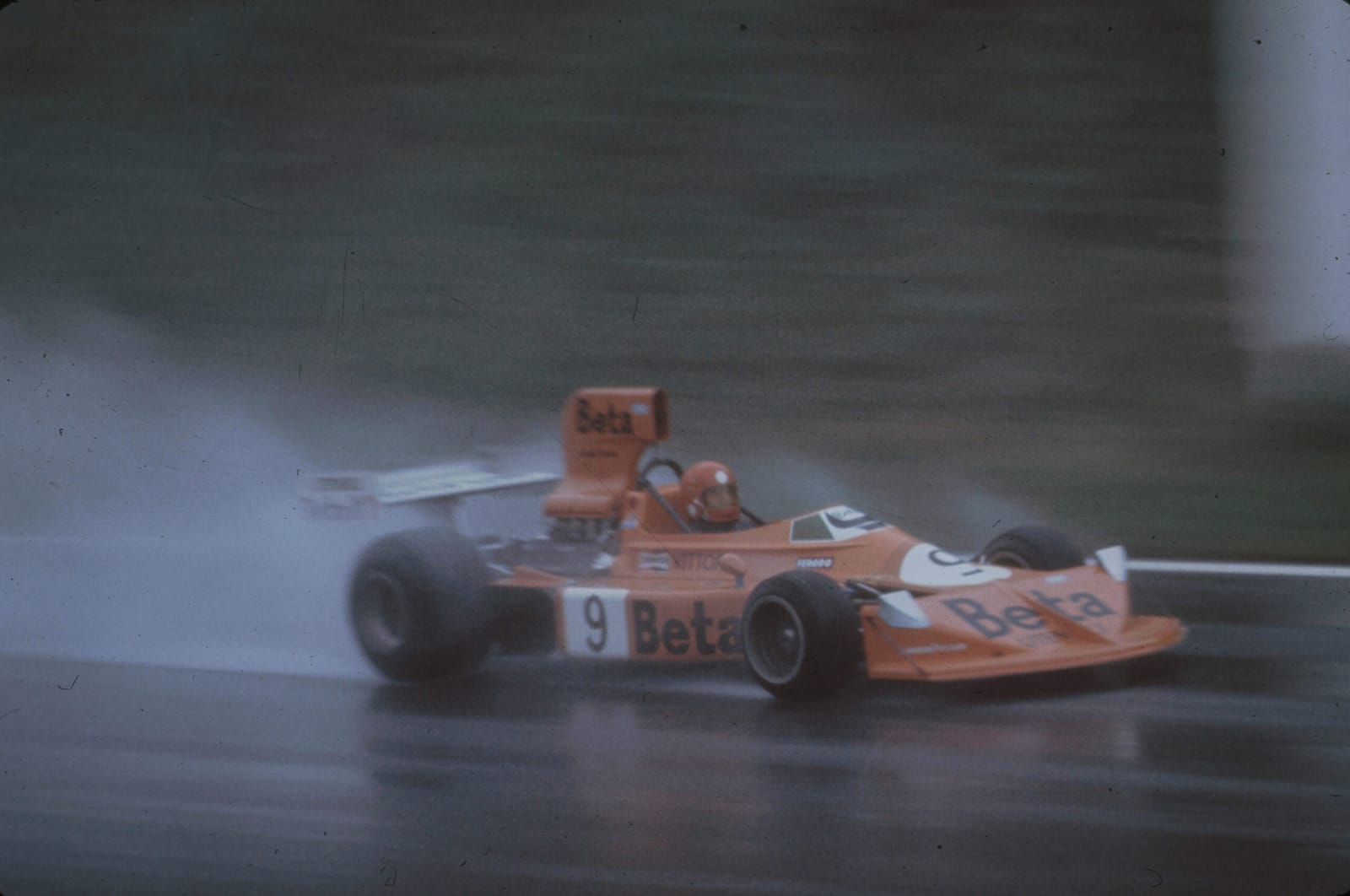 Monoplace orange Beta en course sur une photographie d’archive