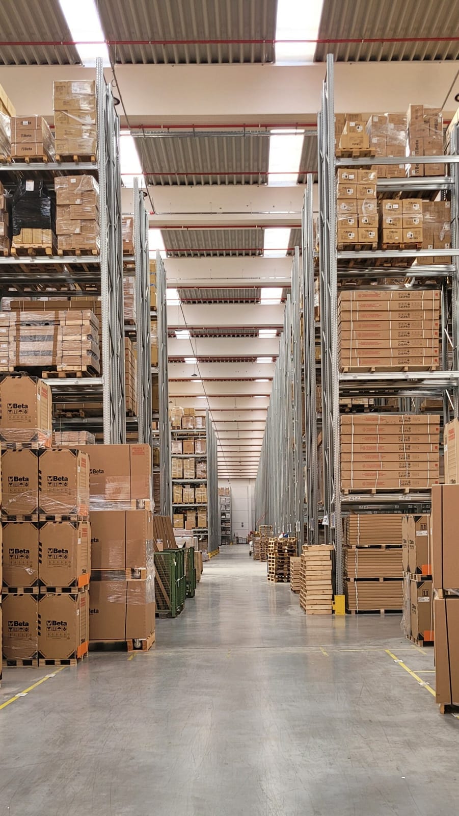 Allée de centre logistique avec palettes et cartons marqués Beta