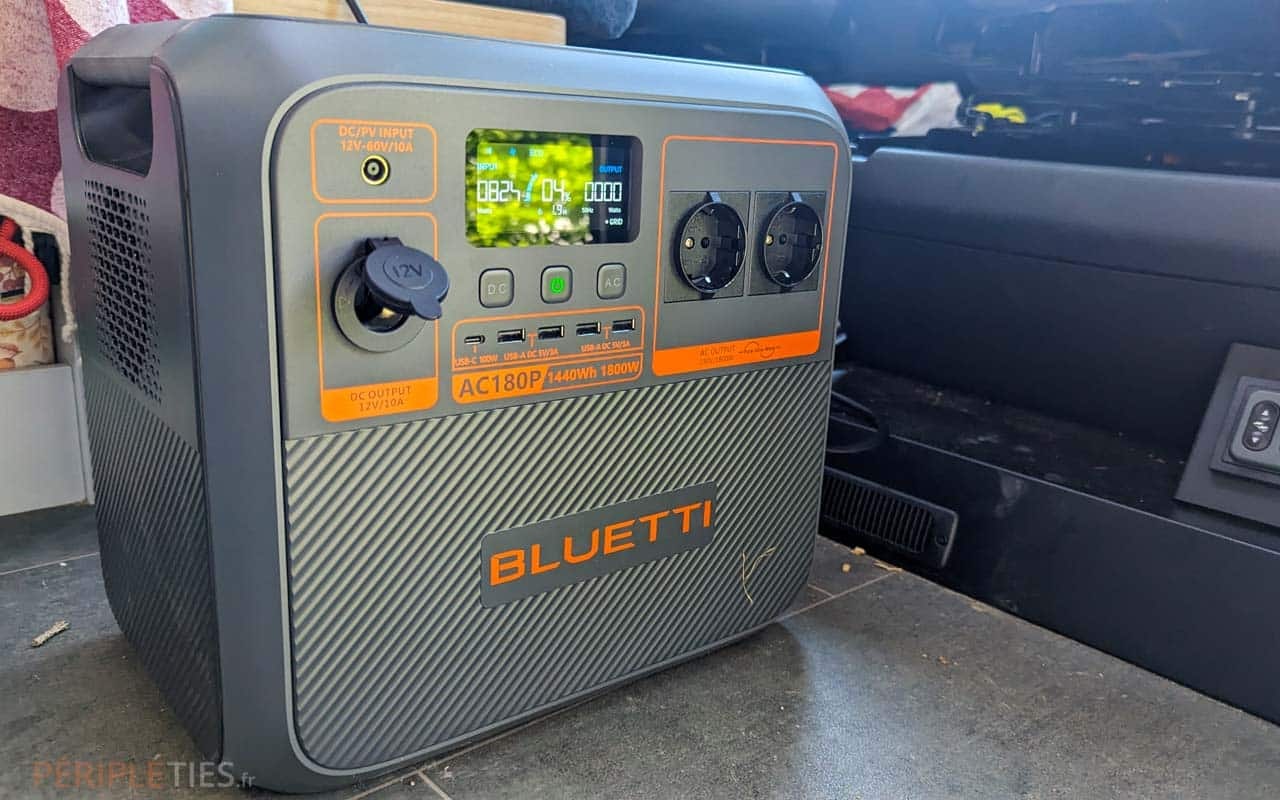 Station d’alimentation portable grise et orange Bluetti AC180P avec écran allumé, posée dans un espace de rangement.