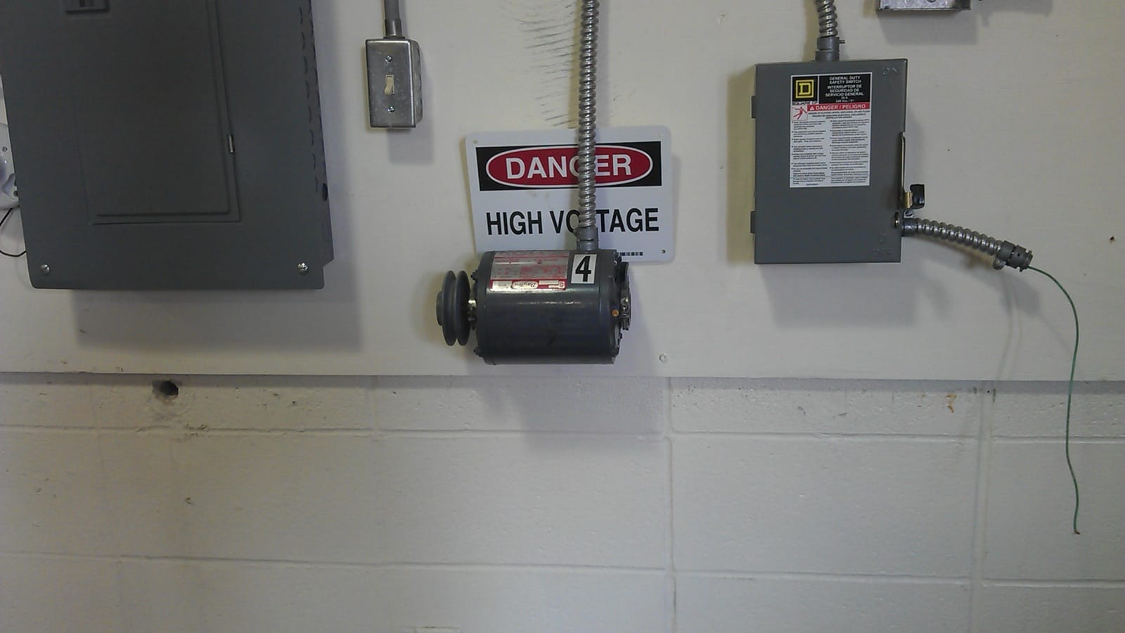 Panneau d'entraînement électrique avec coffrets, conduits métalliques et signalisation de danger