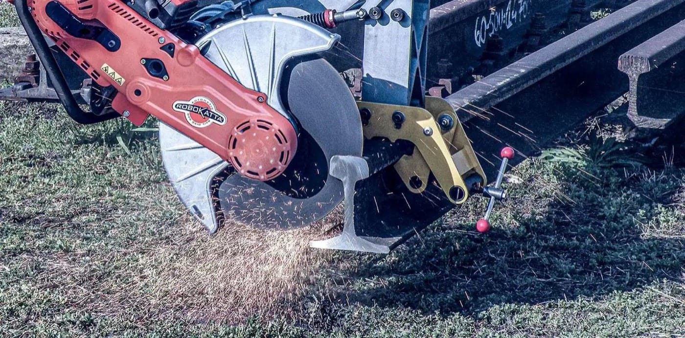 Machine Cembre de découpe de rail avec disque et gerbe d'étincelles sur une voie ferrée