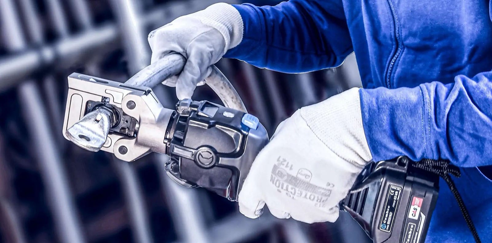 Sertisseuse électro-hydraulique Cembre à batterie utilisée pour sertir un câble, tête ouverte, opérateur ganté