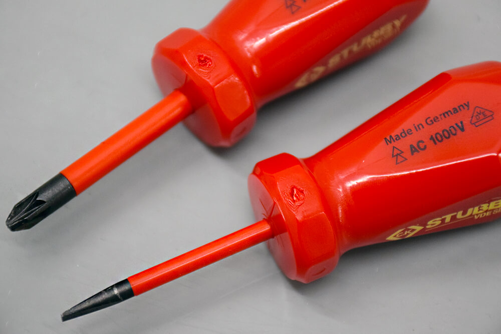 Gros plan sur deux tournevis à manche rouge avec tige orange, portant les inscriptions Made in Germany, AC 1000V et STUBBY.