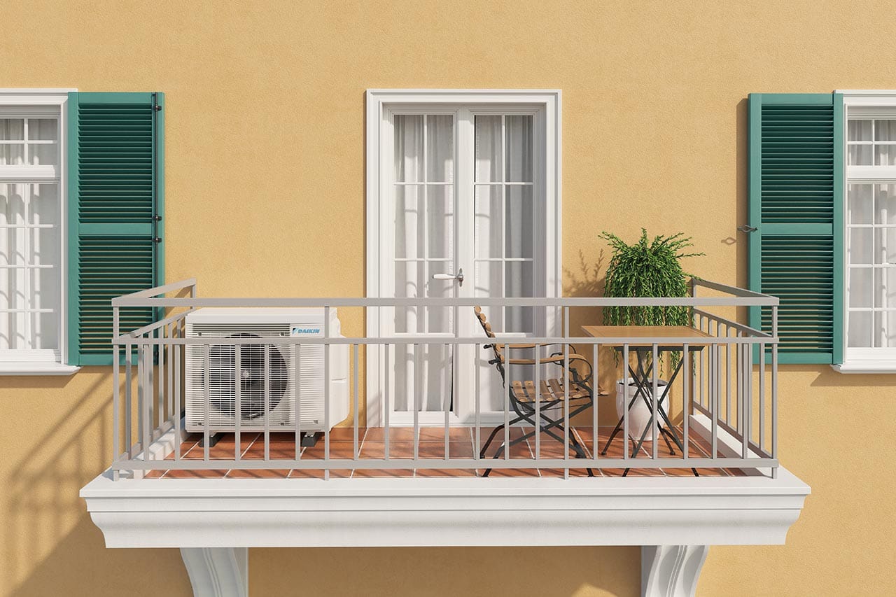 Unité extérieure Daikin installée sur le balcon d’un appartement devant une façade jaune