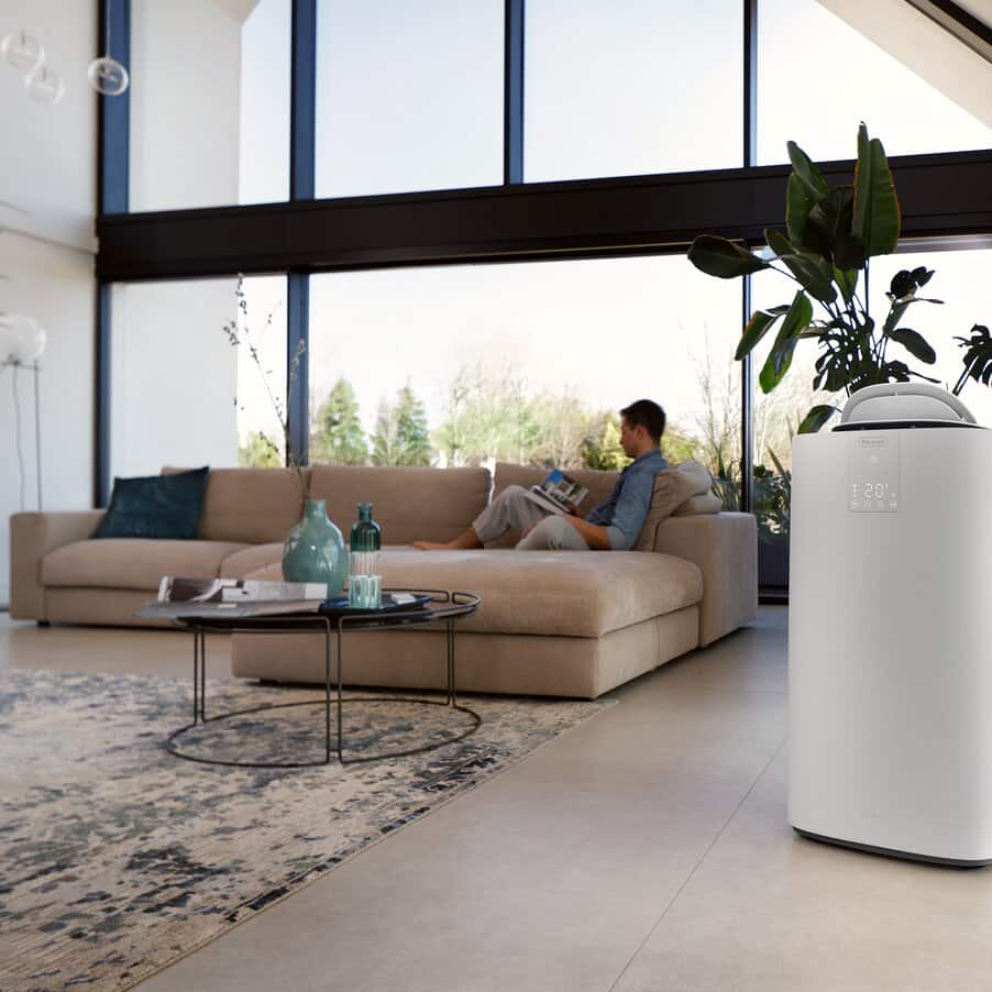 Climatiseur mobile De’Longhi Pinguino installé dans un séjour près d’une fenêtre