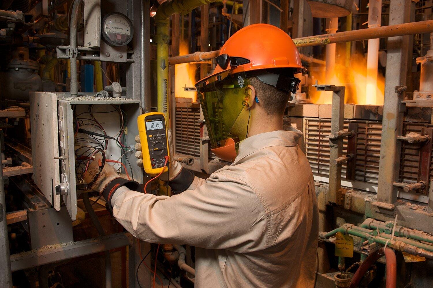 Technicien contrôlant un coffret électrique avec un multimètre Fluke en milieu industriel